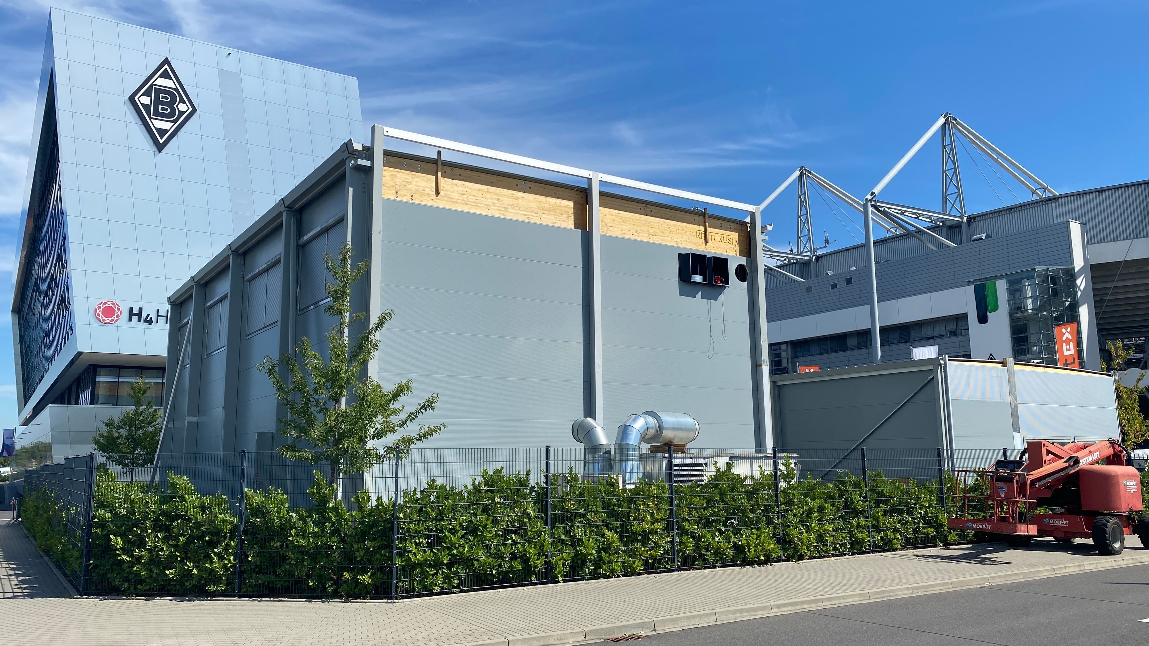 Auf dem Parkplatz P10 im Borussia-Park entsteht der neue Kraftraum für die Profis von Borussia Mönchengladbach. Im Vordergrund steht der Neubau, im Hintergrund sind das Stadion und das H-Hotel zu sehen.