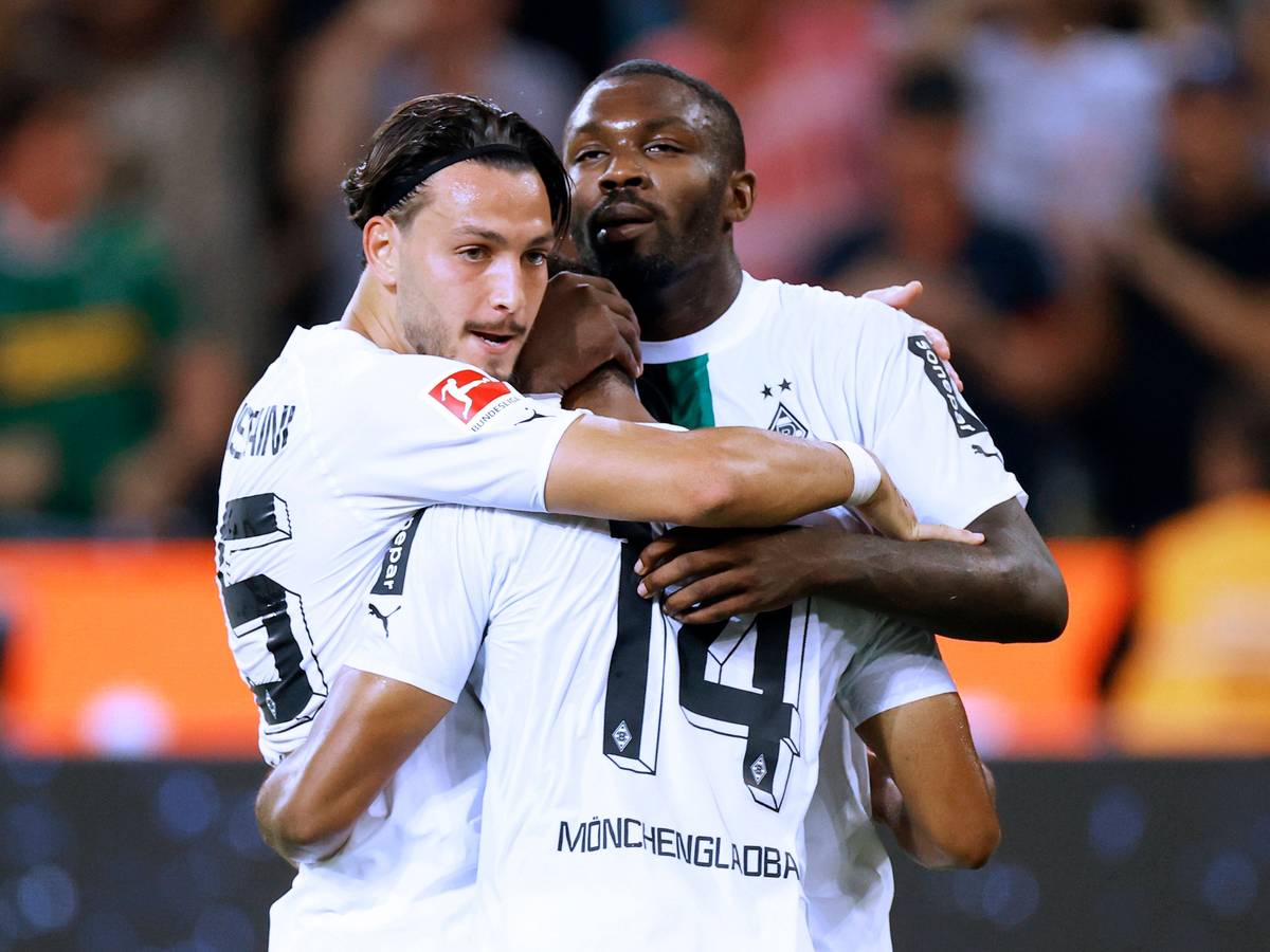 Gehen diese Gladbach-Profis bald getrennte Weg? Ramy Bensebaini (l.) und Marcus Thuram (r.) jubeln gemeinsam mit Alassane Plea (M.) am 19. August 2022 im Bundesliga-Duell gegen Hertha BSC. Die Spieler umarmen sich.