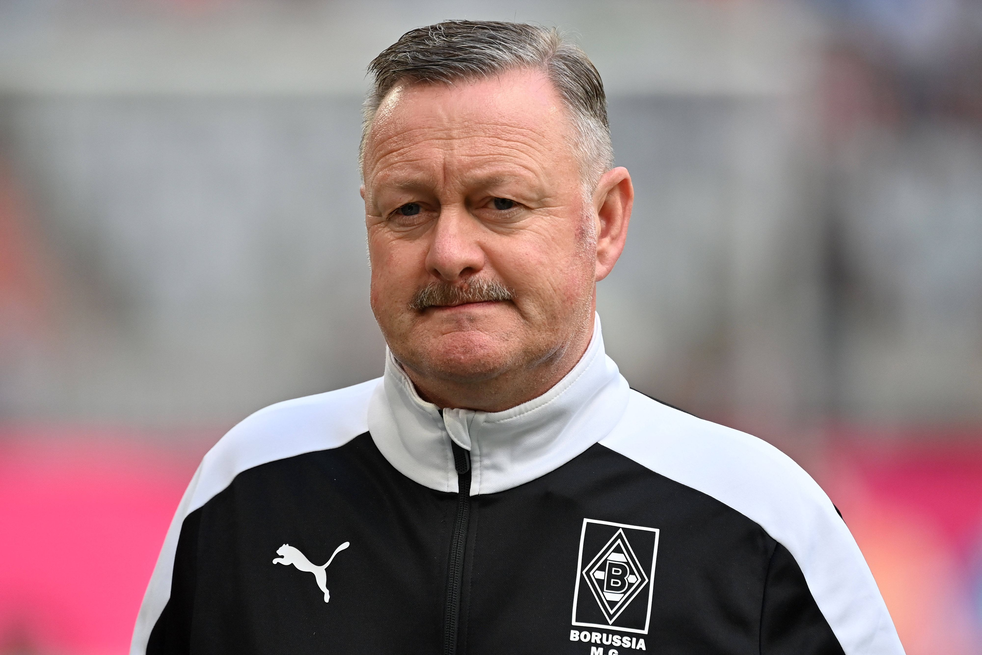 Sportdirektor Roland Virkus von Fußball-Bundesligist Borussia Mönchengladbach, hier zu sehen am Samstag (27. August 2022) am Rande des Bundesliga-Topspiels beim FC Bayern München. Virkus trägt eine schwarz-weiße Trainingsjacke.