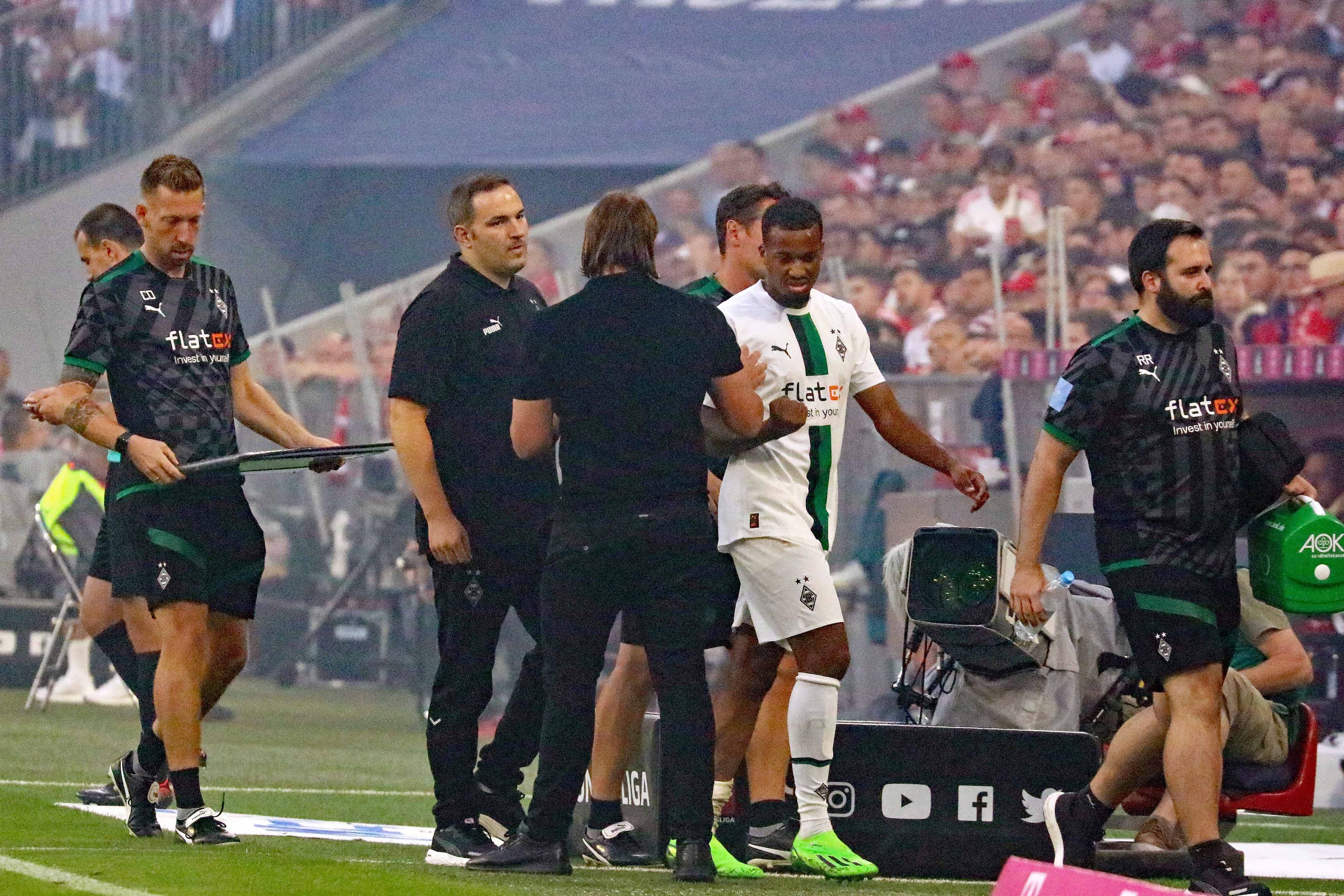 Gladbach-Stürmer Alassane Plea verlässt angeschlagen das Spielfeld während des Bundesliga-Topspiels (27. August 2022) der Borussia beim FC Bayern München. Plea klatscht Trainer Daniel Farke ab.