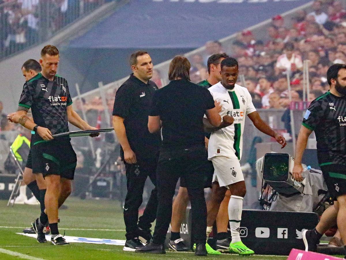 Gladbach-Stürmer Alassane Plea verlässt angeschlagen das Spielfeld während des Bundesliga-Topspiels (27. August 2022) der Borussia beim FC Bayern München. Plea klatscht Trainer Daniel Farke ab.