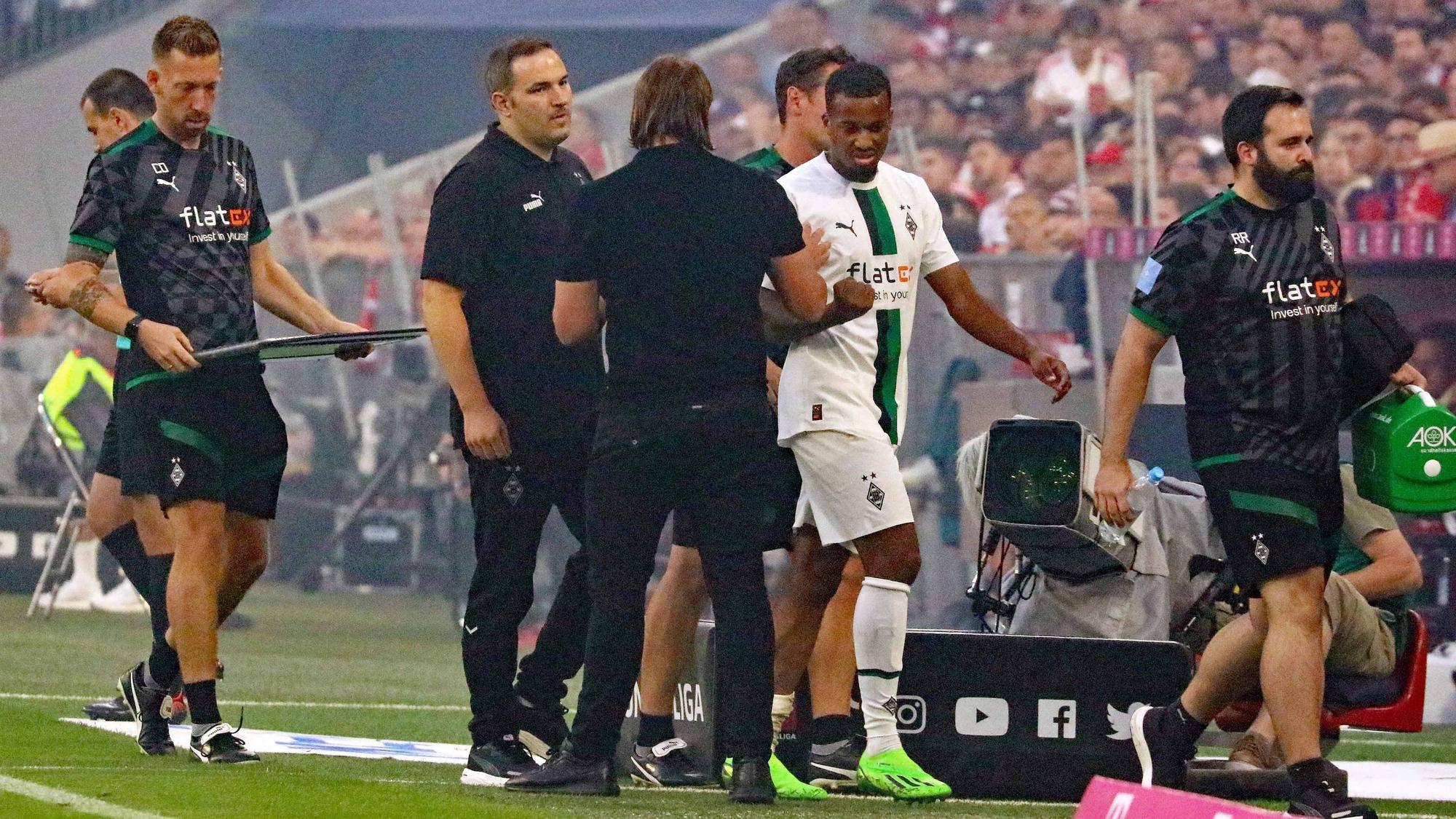 Gladbach-Stürmer Alassane Plea verlässt angeschlagen das Spielfeld während des Bundesliga-Topspiels (27. August 2022) der Borussia beim FC Bayern München. Plea klatscht Trainer Daniel Farke ab.