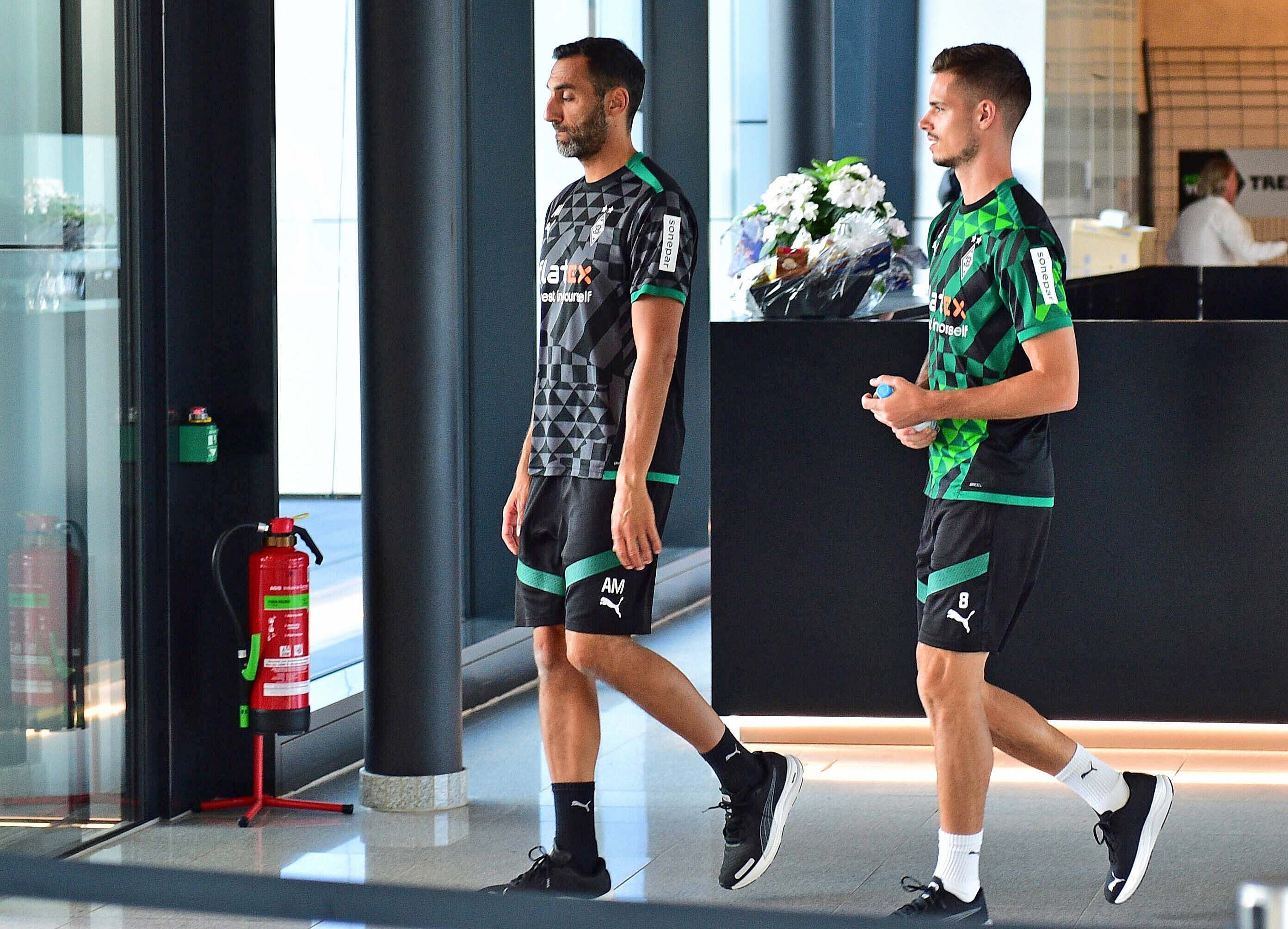 DFB-Nationalspieler und Gladbach-Zugang Julian Weigl (r.), hier zu sehen am Donnerstag (1. September 2022) im Borussia-Park, vor ihm geht Athletik-Trainer Alexander Mouhcine (l.). Weigl hat eine Wasserflasche in seinen Händen.