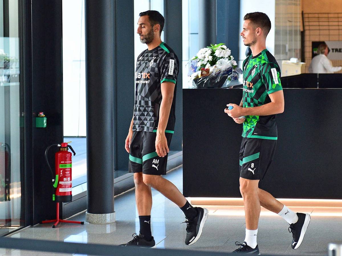 DFB-Nationalspieler und Gladbach-Zugang Julian Weigl (r.), hier zu sehen am Donnerstag (1. September 2022) im Borussia-Park, vor ihm geht Athletik-Trainer Alexander Mouhcine (l.). Weigl hat eine Wasserflasche in seinen Händen.