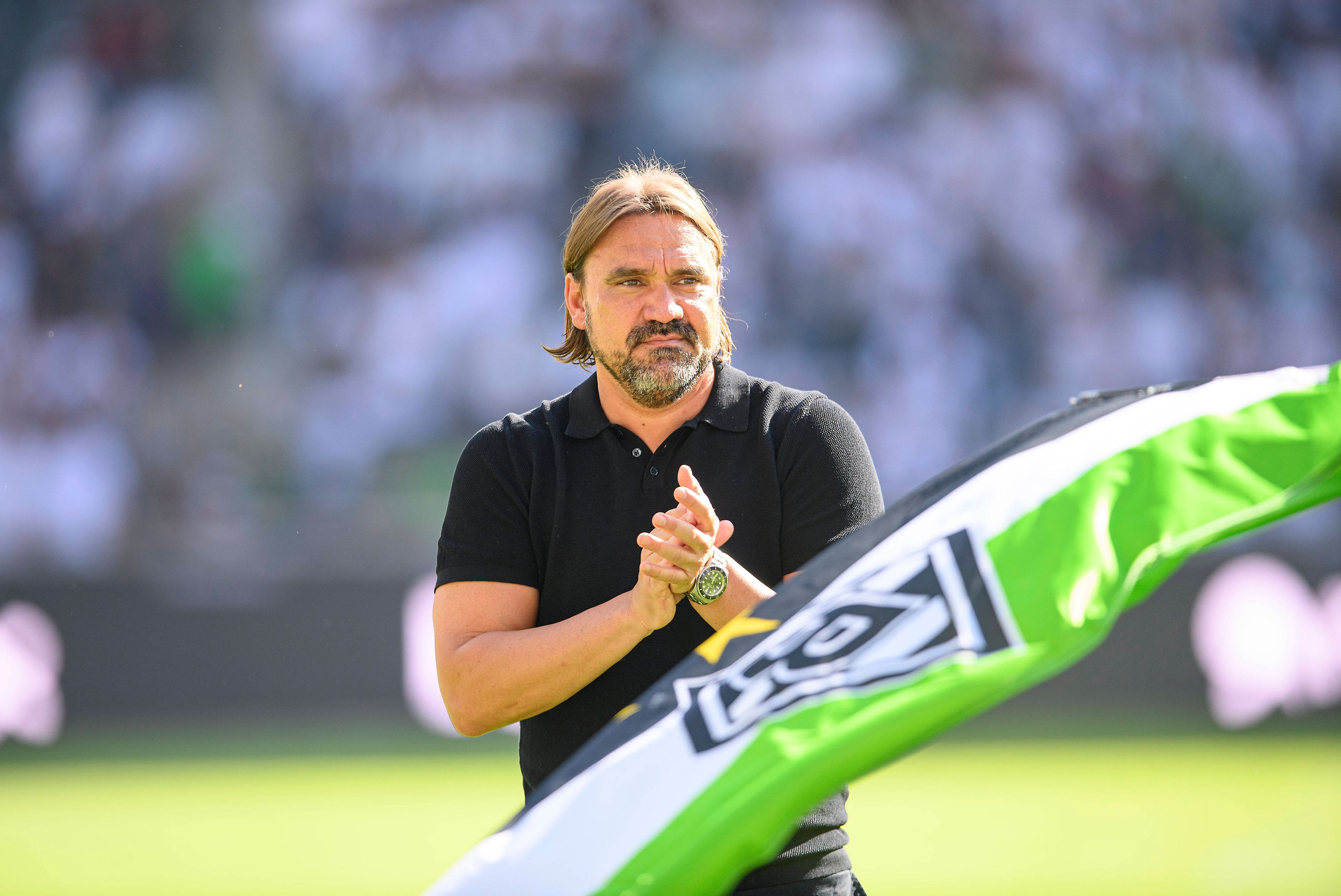 Trainer Daniel Farke bedankt sich nach dem Spiel von Borussia Mönchengladbach gegen die TSG Hoffenheim am 6. August 2022 bei den Fans im Borussia-Park. Farke applaudiert, im Vordergrund ist eine Fahne in den Gladbacher Vereinsfarben zu sehen.
