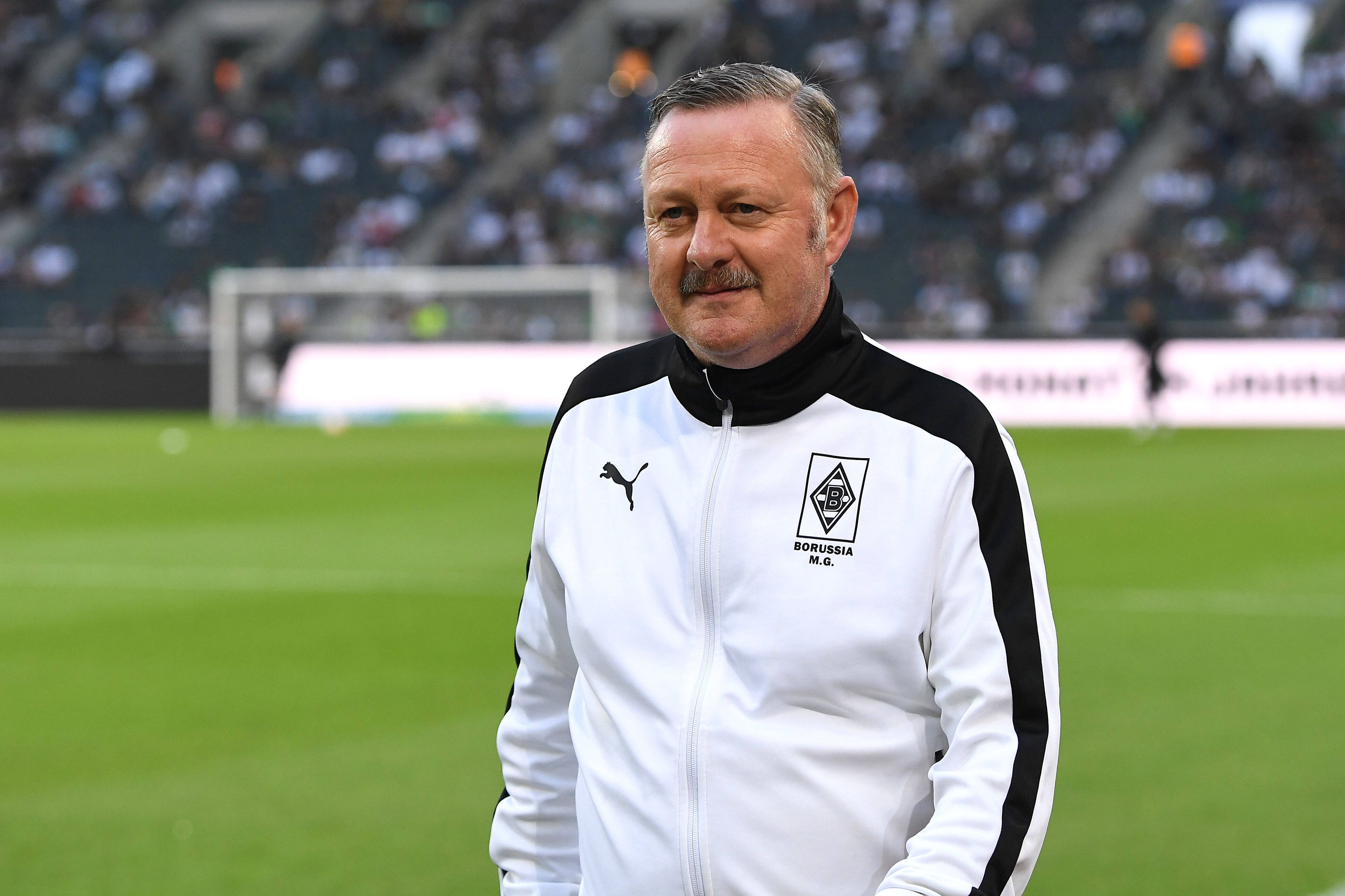 Gladbach-Manager Roland Virkus, hier am 19. August 2022 im Borussia-Park vor der Bundesliga-Partie der Fohlen-Elf gegen Hertha BSC zu sehen. Virkus trägt eine weiß-schwarze Trainingsjacke von Puma mit Borussia-Logo.