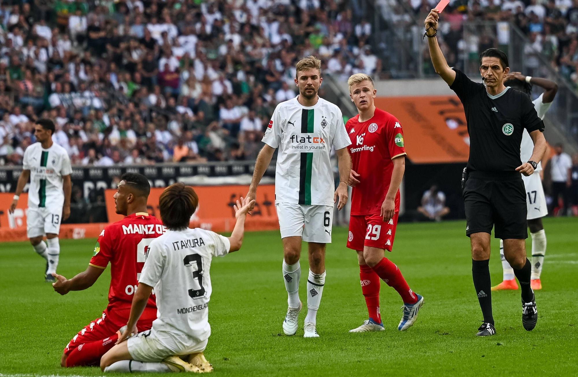 Schiedsrichter Deniz Aytekin (r.) zeigt Gladbach-Verteidiger Ko Itakura (kniend, im weißen Trikot) die Rote Karte nach einer Notbremse im Bundesliga-Duell gegen Mainz 05 (4. September 2022) im Borussia-Park. Aytekin hält die Rote Karte in der Hand.