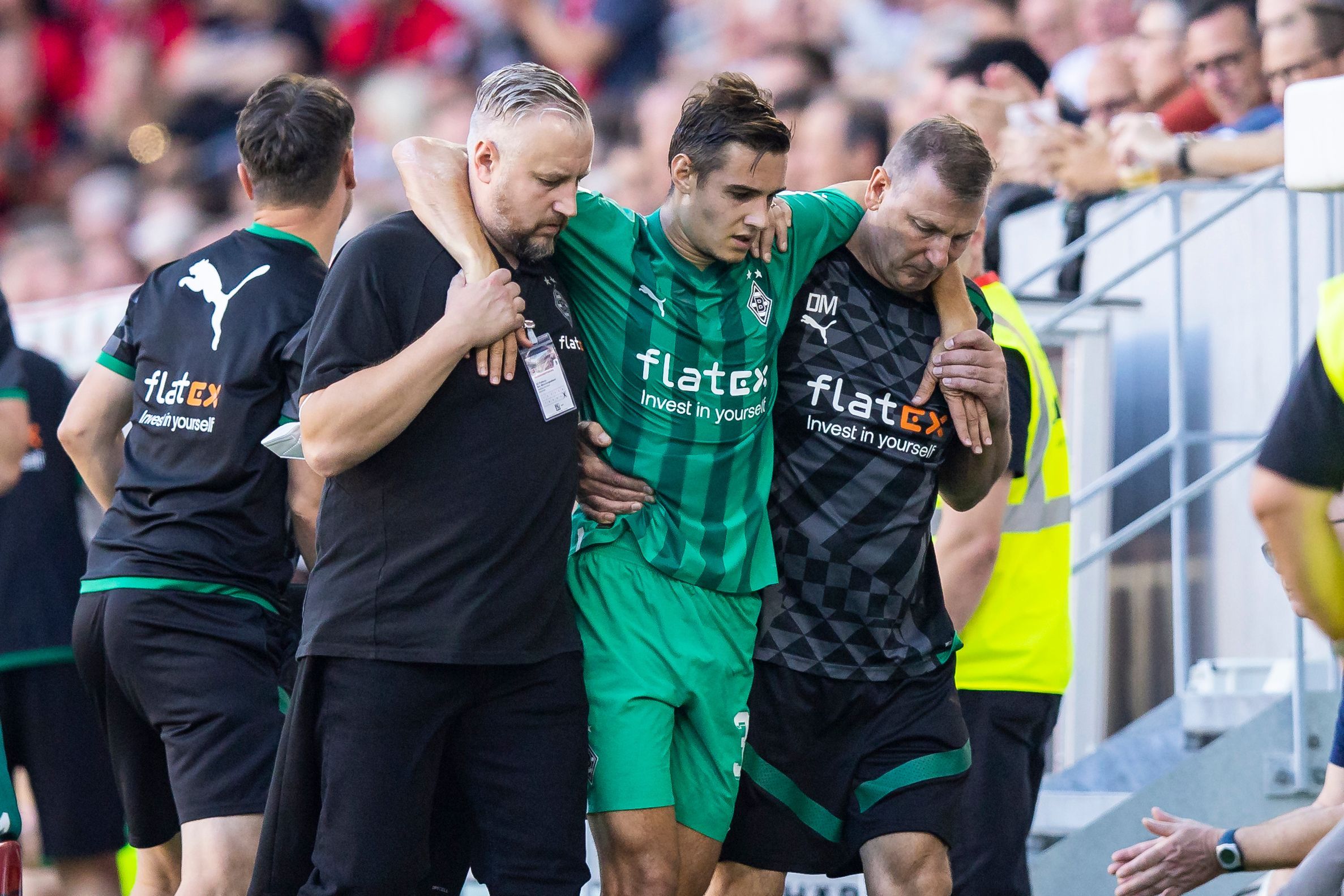 Gladbach-Profi Florian Neuhaus (M.) wird verletzt am Sonntag (11. September 2022) in Freiburg vom Platz getragen. Er wird von Betreuern gestützt.