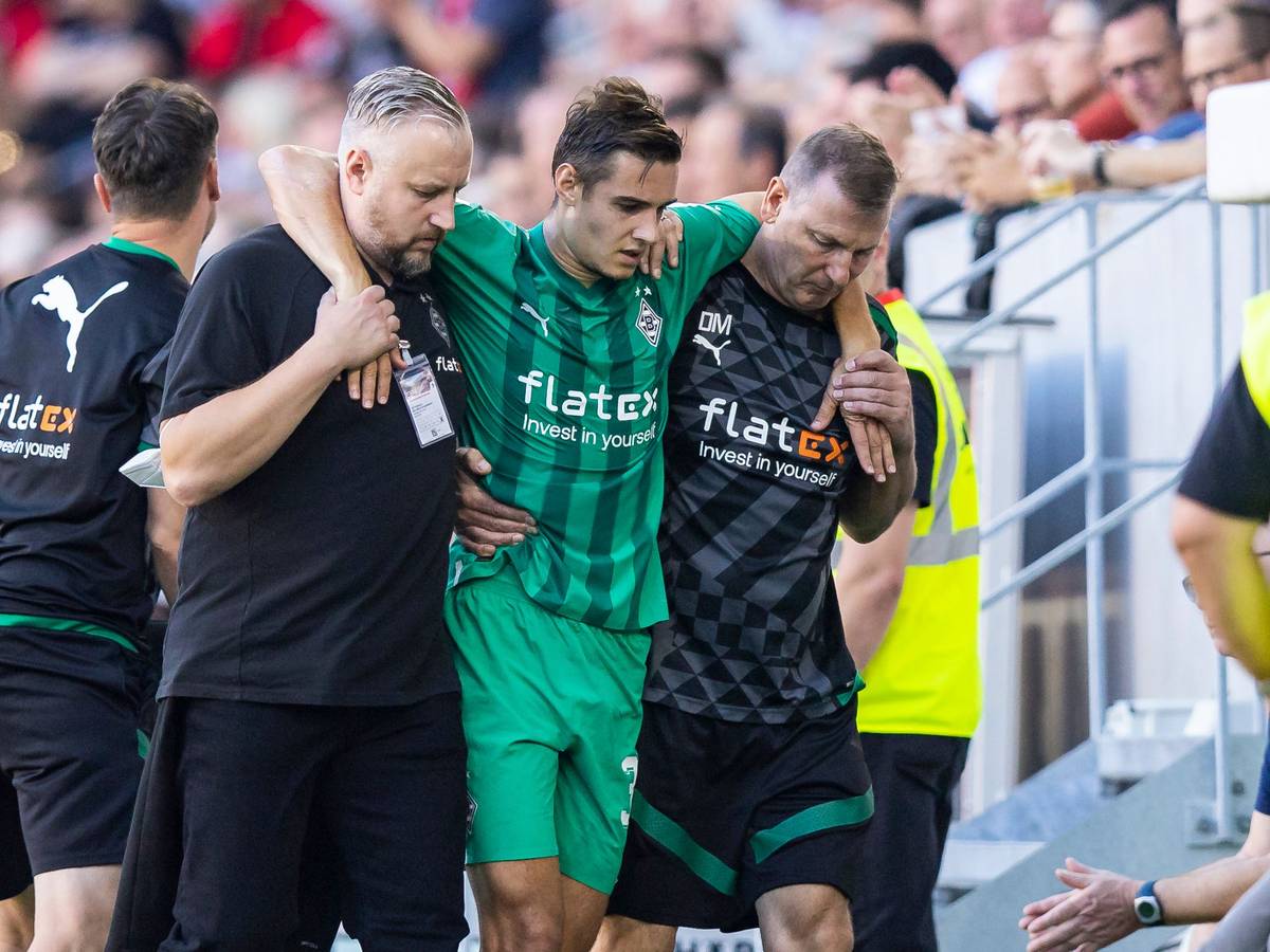 Gladbach-Profi Florian Neuhaus (M.) wird verletzt am Sonntag (11. September 2022) in Freiburg vom Platz getragen. Er wird von Betreuern gestützt.
