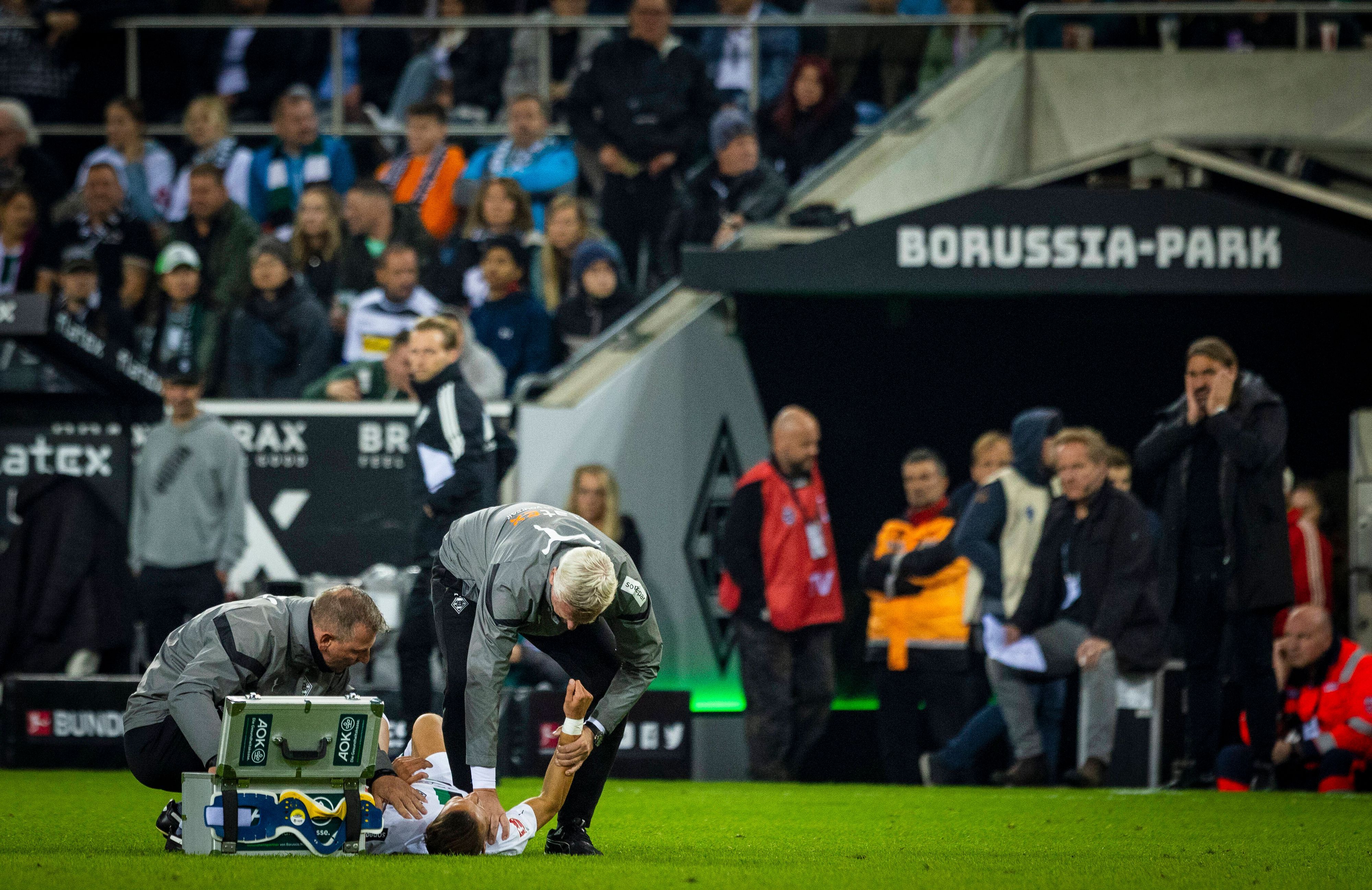 Physiotherapeut Dirk Müller (l). und Mannschaftsarzt Stefan Hertl (r.) kümmern sich um Hannes Wolf (Mitte) von Borussia Mönchengladbach.