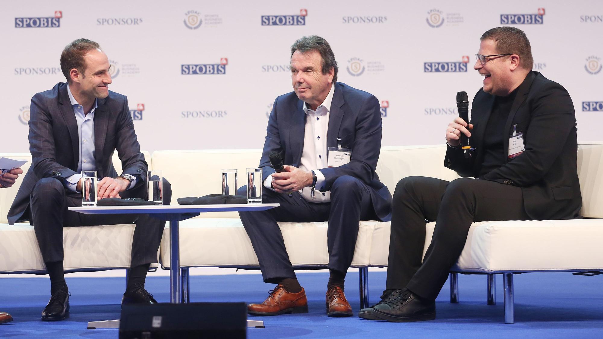 Gute Laune: Geschäftsführer Oliver Mintzlaff von RB Leipzig (l.) mit Heribert Bruchhagen (M.), Ex-Vorstand Hamburger SV, und Ex-Gladbach-Manager Max Eberl (r.) während des Sportbusiness-Kongress „SPOBIS“ am 30. Januar 2018 in Düsseldorf. Eberl hält ein Mikrofon in der Hand.