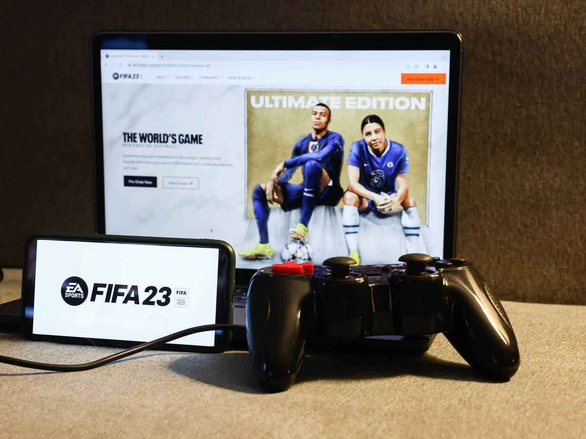 Am 27. September 2022 erscheint die neue Version des Konsolen-Klassikers FIFA. Auf dem Foto ist das Logo des neuen Teils auf einem Smartphone zu sehen, im Hintergrund zeigt ein Laptop das voraussichtliche Cover.