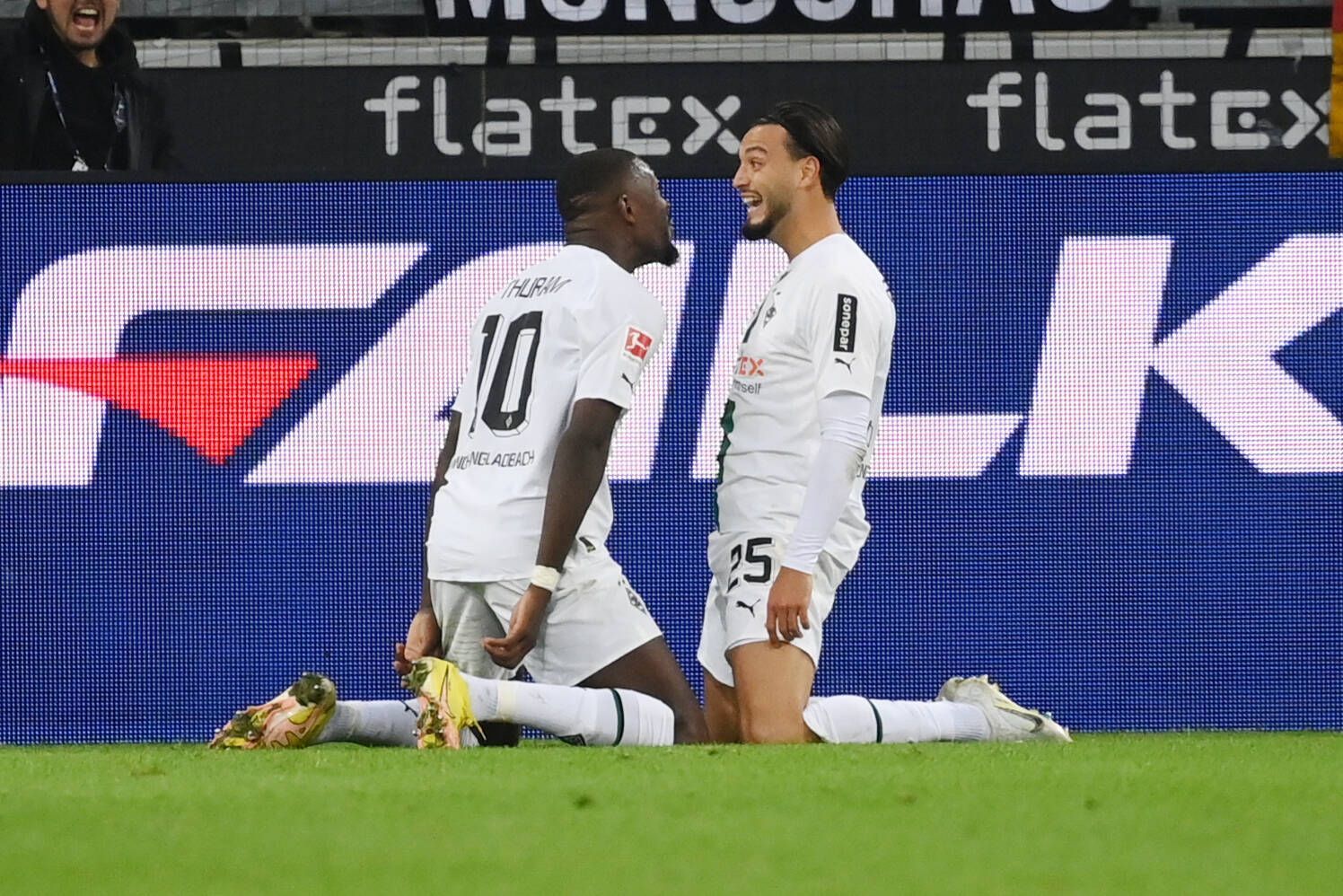Gladbach-Profi Ramy Bensebaini (l.) jubelt gemeinsam mit Marcus Thuram über seinen Bundesliga-Treffer beim 3:0-Sieg gegen RB Leipzig am 17. September 2022 im Borussia-Park. Beide Spieler knien auf dem Rasen.