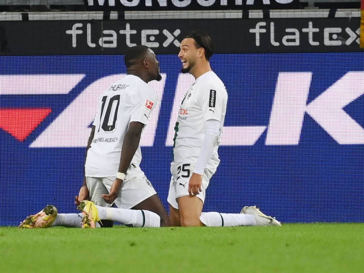 Gladbach-Profi Ramy Bensebaini (l.) jubelt gemeinsam mit Marcus Thuram über seinen Bundesliga-Treffer beim 3:0-Sieg gegen RB Leipzig am 17. September 2022 im Borussia-Park. Beide Spieler knien auf dem Rasen.