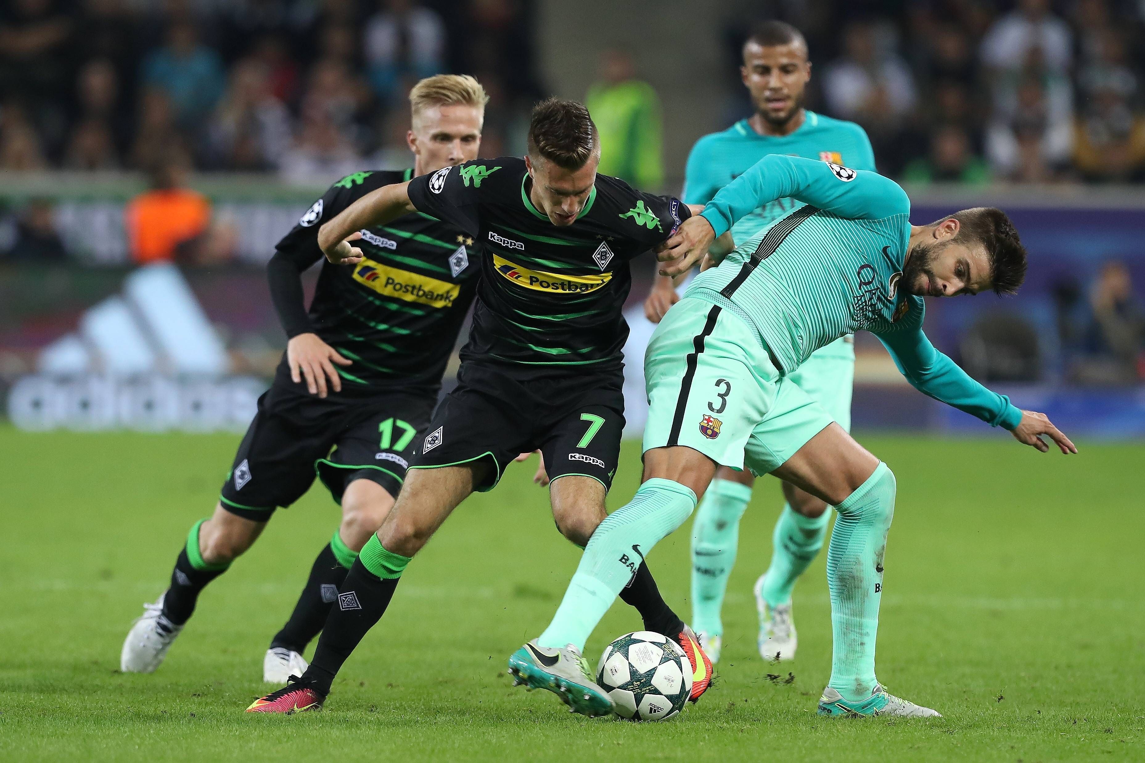 Gladbach-Profi Patrick Herrmann (Mitte) im Champions-League-Duell am 28. September 2016 mit dem FC Barcelona im Borussia-Park. In dieser Szene befindet sich der Flügelflitzer im Zweikampf mit Abwehrspieler Gerard Piqué. Beide Spieler haben jeweils den Ball im Blick.