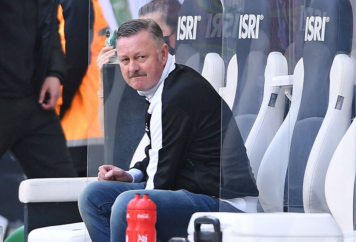 Ein enttäuschter Blick: Gladbach-Manager Roland Virkus sitzt bei der Derby-Niederlage gegen den 1. FC Köln am 16. April 2022 auf der Spielerbank im Borussia-Park. Virkus trägt eine schwarz-weiße Puma-Jacke.