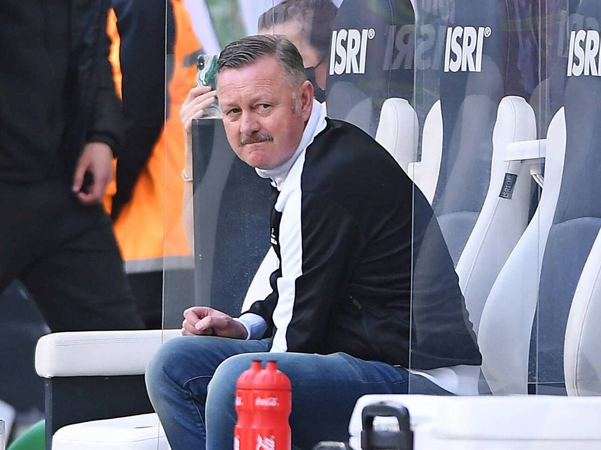 Ein enttäuschter Blick: Gladbach-Manager Roland Virkus sitzt bei der Derby-Niederlage gegen den 1. FC Köln am 16. April 2022 auf der Spielerbank im Borussia-Park. Virkus trägt eine schwarz-weiße Puma-Jacke.