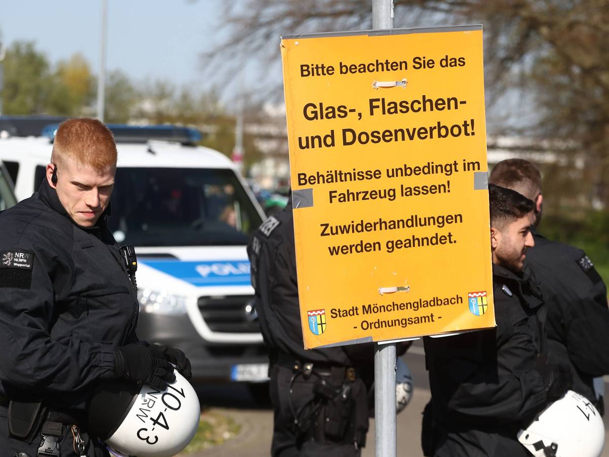 Wie in jedem Jahr wird es rund um das Derby zwischen Borussia Mönchengladbach und dem 1. FC Köln zahlreiche Sicherheitsmaßnahmen geben. Das Foto zeigt Polizeibeamte beim vergangenen Derby am 16. April 2022 mit einem Schild, dass auf das Glas-, Flaschen- und Dosenverbot hinweist.