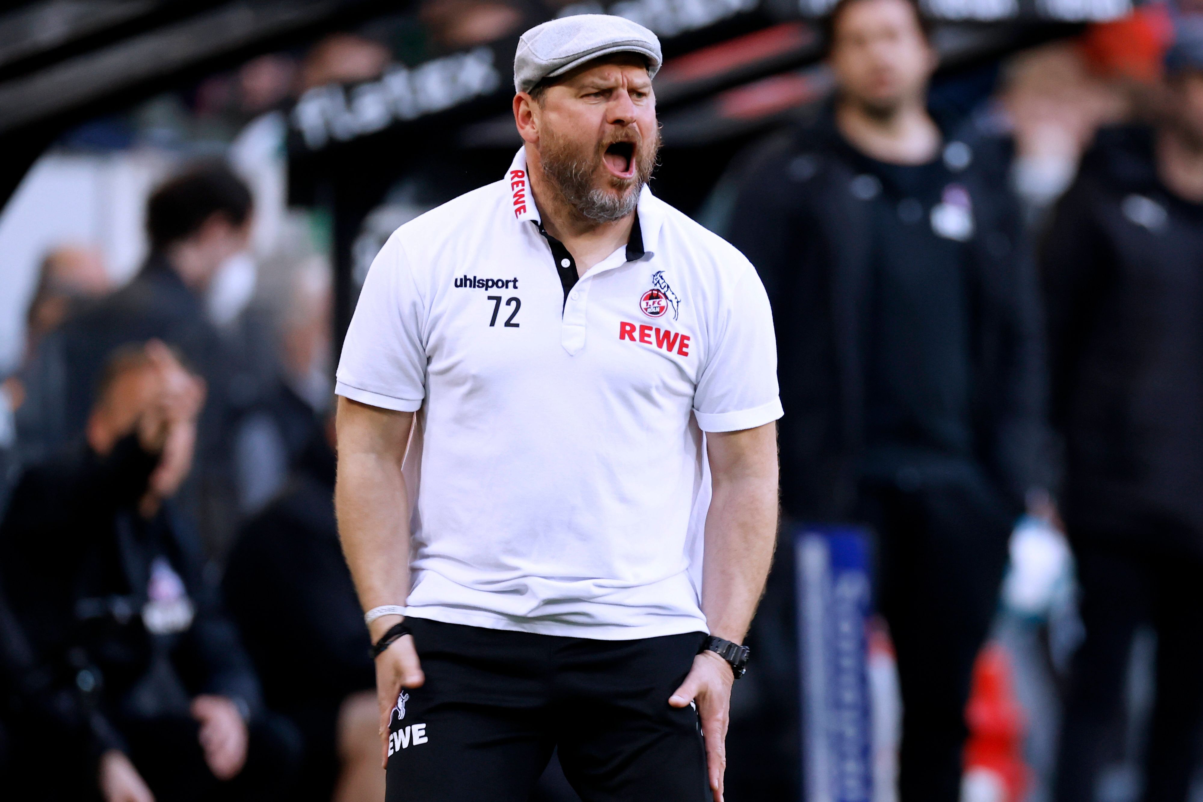 Steffen Baumgart, Trainer des 1. FC Köln, gestikuliert und schreit an der Seitenlinie im Gladbacher Borussia-Park. Dieses Foto stammt vom 16. April 2022. Baumgart trägt eine Jogginghose und ein weißes Polohemd, dazu eine Schiebermütze.