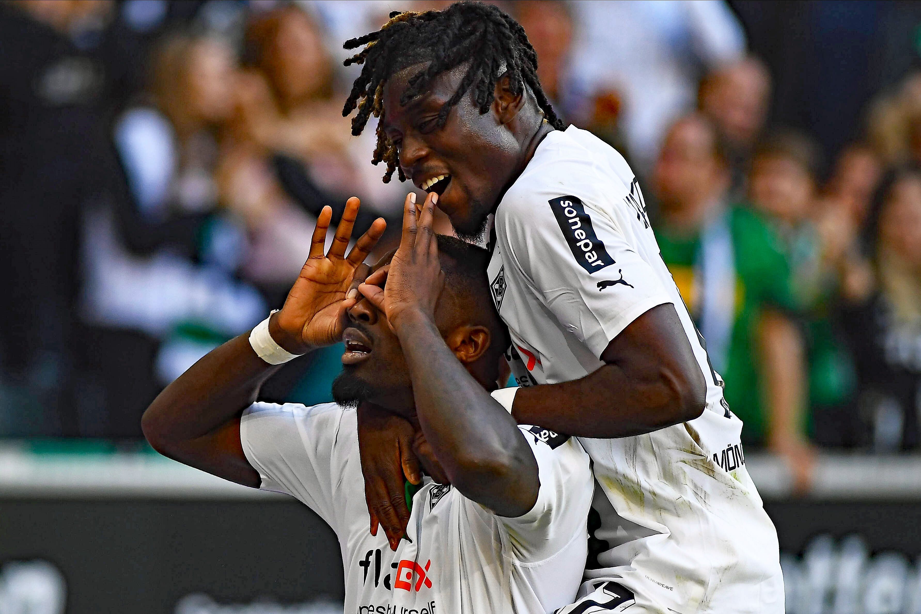 Stürmer Marcus Thuram (l.) von Borussia Mönchengladbach hat beim Derbysieg gegen den 1. FC Köln am Sonntag (9. Oktober 2022) zum 5:2-Endstand getroffen. Das Foto zeigt ihn beim Torjubel, bei dem er den Brillenjubel von Ex-Köln-Profi Anthony Modest imitiert. Teamkollege Manu Koné (r.) jubelt mit. Thuram macht eine Geste mit seinen Händen.