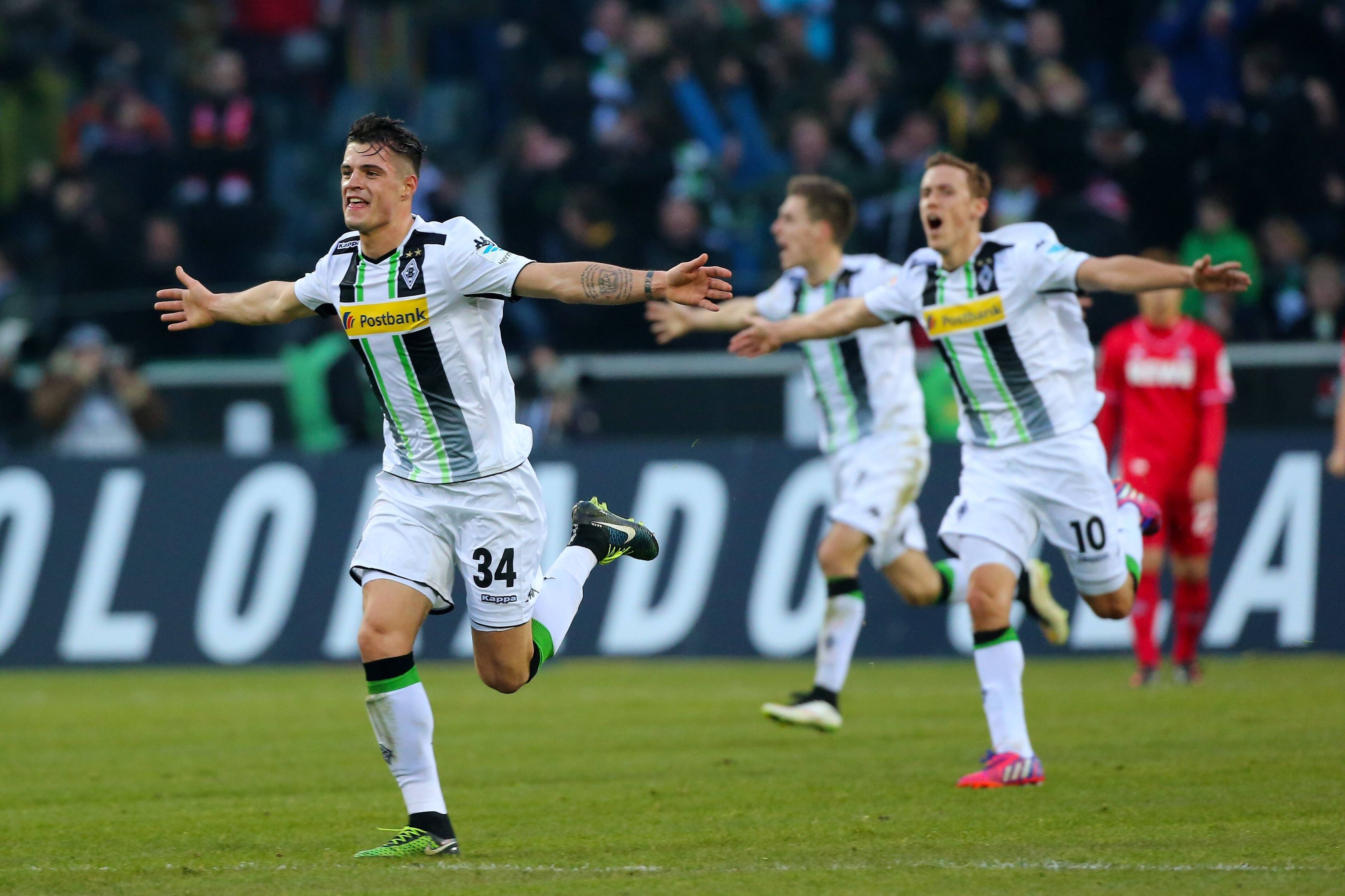 Granit Xhaka läuft nach seinem Last-Minute-Treffer für Borussia Mönchengladbach gegen den 1. FC Köln am in Richtung Nordkurve. Xhaka hat die Arme ausgebreitet, im Hintergrund sind Max Kurse und Patrick Herrmann ebenfalls mit ausgebreiteten Armen zu sehen.