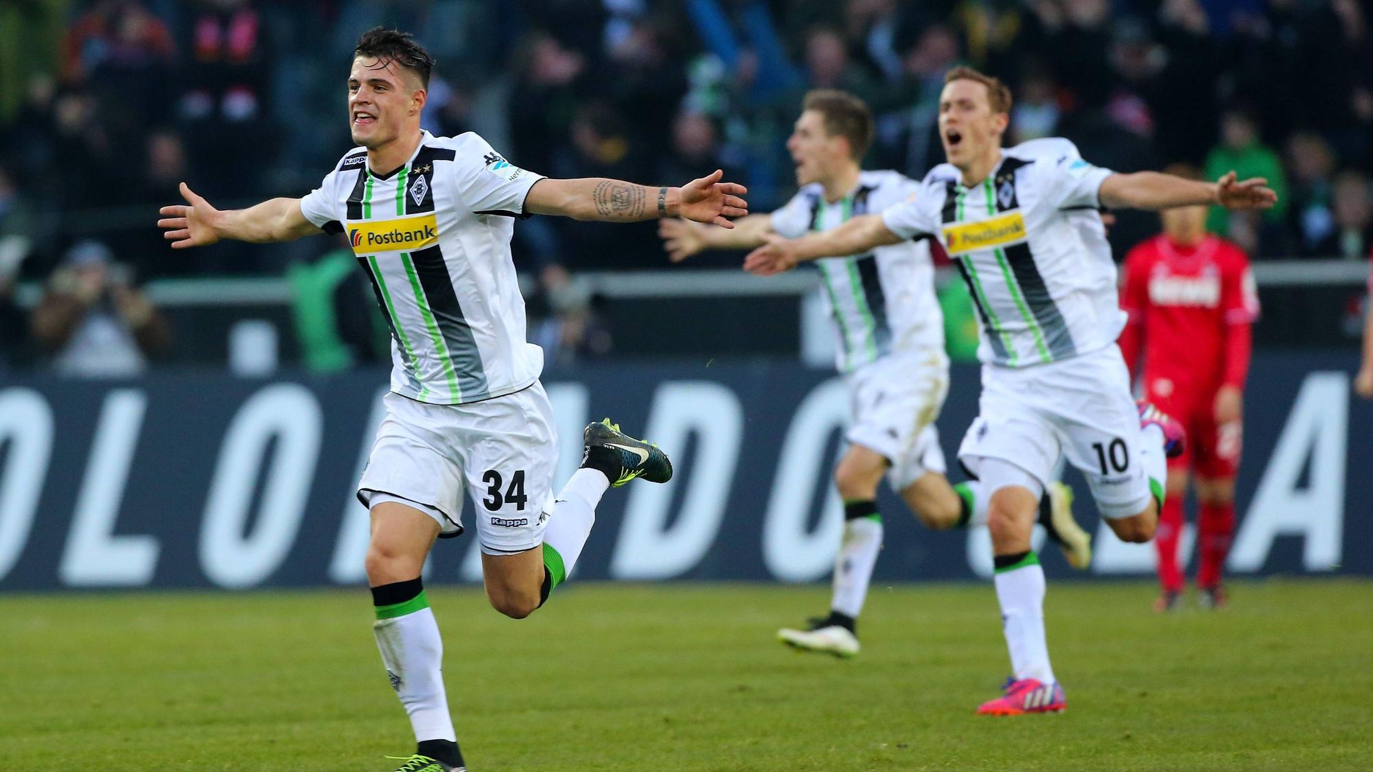 Granit Xhaka läuft nach seinem Last-Minute-Treffer für Borussia Mönchengladbach gegen den 1. FC Köln am in Richtung Nordkurve. Xhaka hat die Arme ausgebreitet, im Hintergrund sind Max Kurse und Patrick Herrmann ebenfalls mit ausgebreiteten Armen zu sehen.