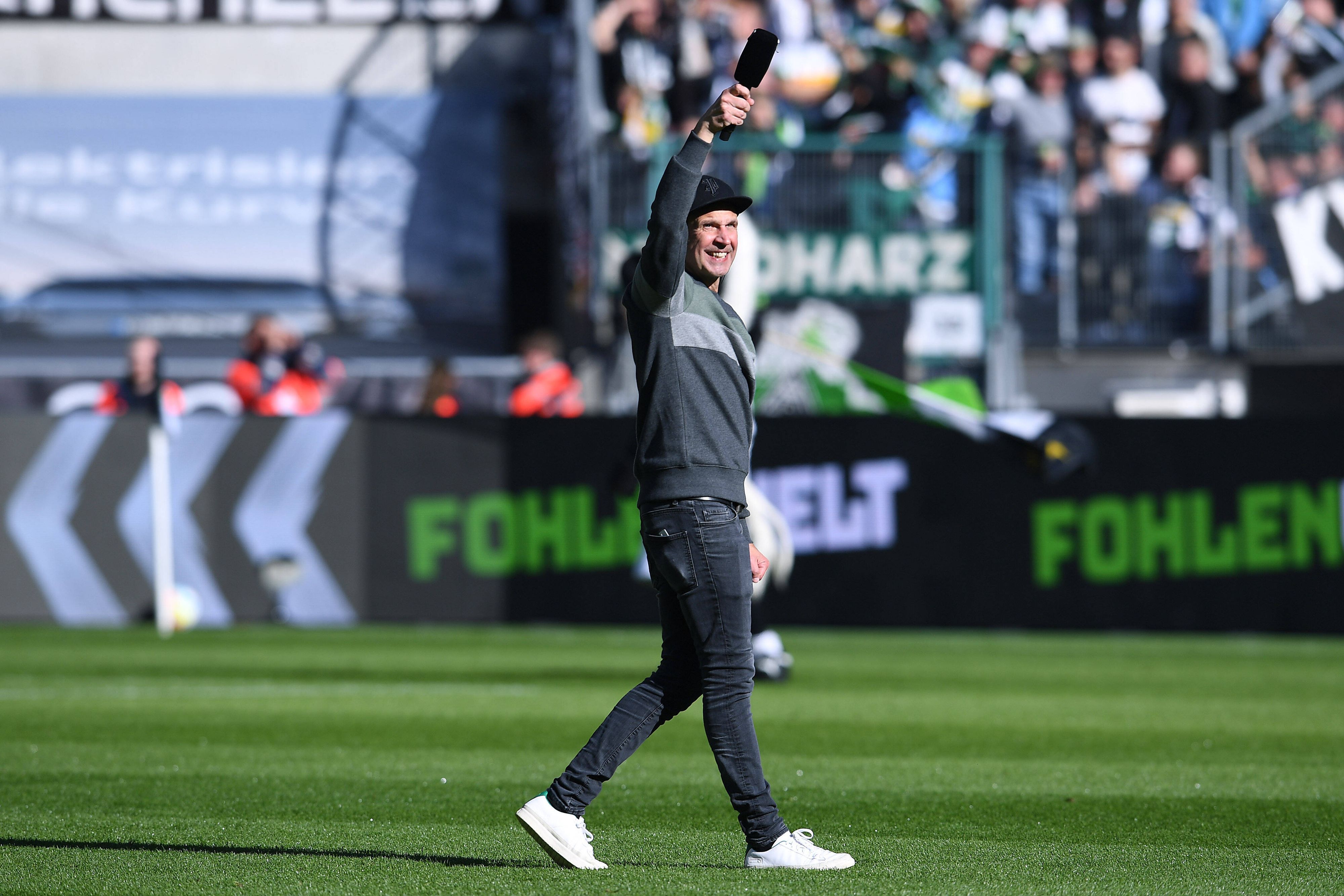 Stadionsprecher Torsten „Knippi“ Knippertz am 9. Oktober 2022 vor dem Bundesliga-Heimspiel von Borussia Mönchengladbach gegen den 1. FC Köln. Knippertz steht auf dem Rasen im Borussia-Park, in der rechten Hand hält er ein Mikrofon.
