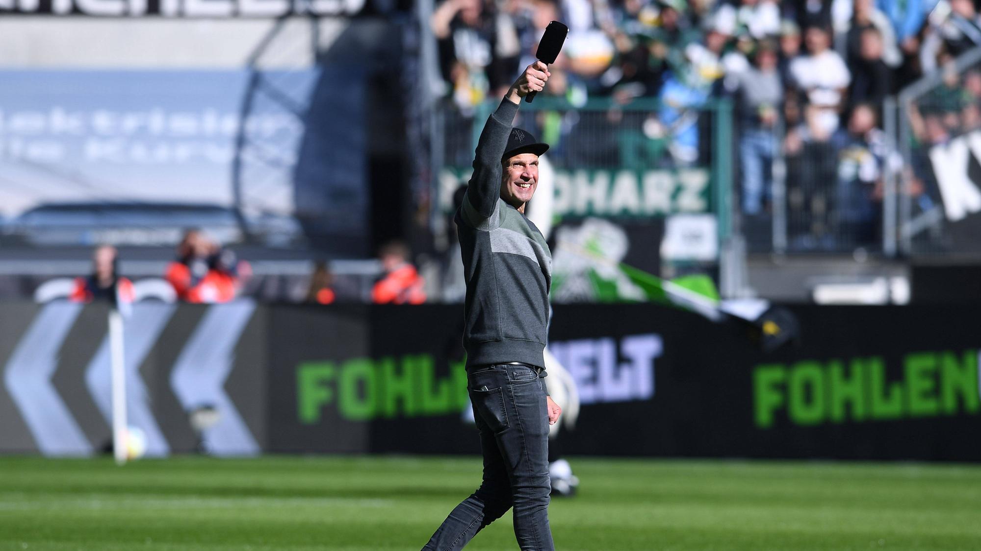 Stadionsprecher Torsten „Knippi“ Knippertz am 9. Oktober 2022 vor dem Bundesliga-Heimspiel von Borussia Mönchengladbach gegen den 1. FC Köln. Knippertz steht auf dem Rasen im Borussia-Park, in der rechten Hand hält er ein Mikrofon.