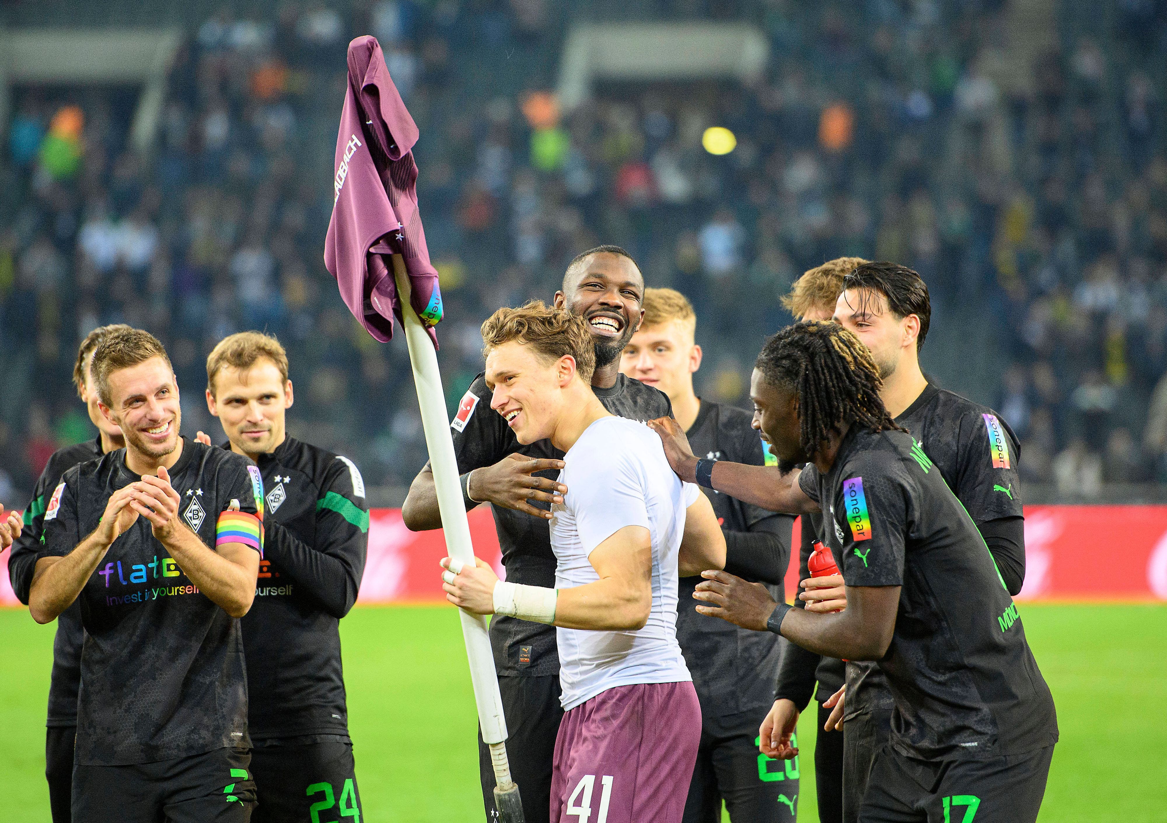 Jubel im Borussia-Park: Die Gladbach-Profis um Stürmer Marcus Thuram feiern nach der 4:2-Gala (11. November 2022) gegen Borussia Dortmund den Heim-Dreier und Torhüter-Talent Jan Olschowsky, der stark gehalten hatte. Olschowsky hält die Eckfahne mit seinem Trikot in der linken Hand.