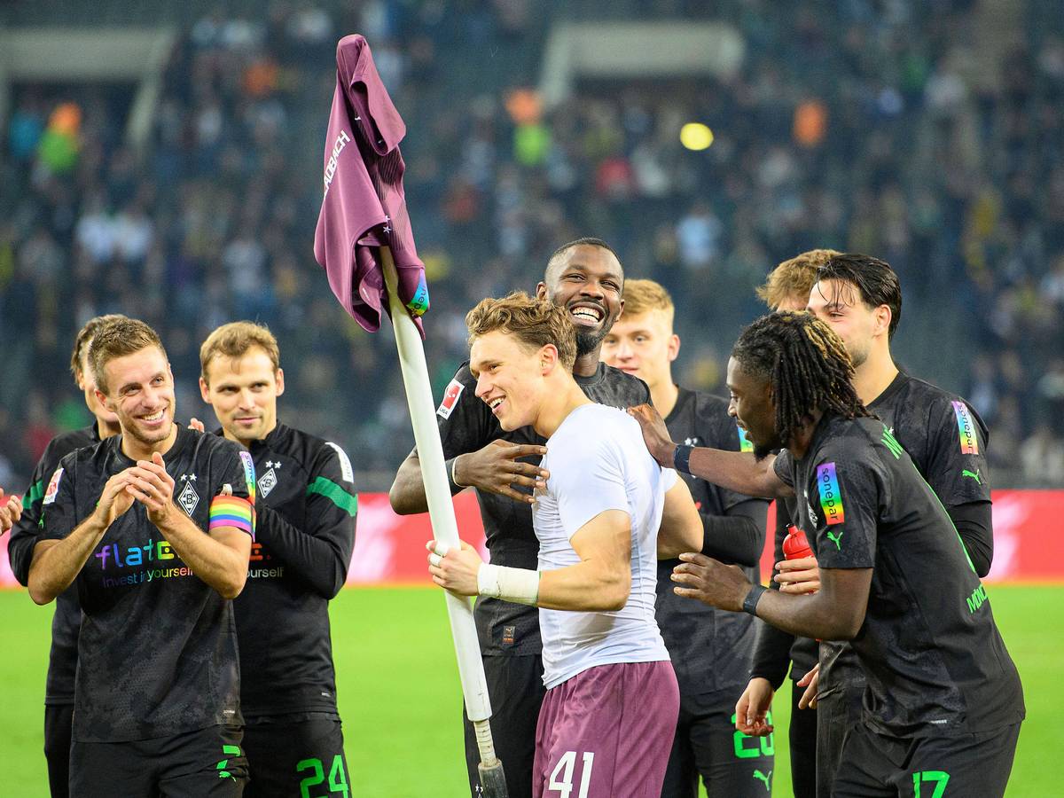 Jubel im Borussia-Park: Die Gladbach-Profis um Stürmer Marcus Thuram feiern nach der 4:2-Gala (11. November 2022) gegen Borussia Dortmund den Heim-Dreier und Torhüter-Talent Jan Olschowsky, der stark gehalten hatte. Olschowsky hält die Eckfahne mit seinem Trikot in der linken Hand.