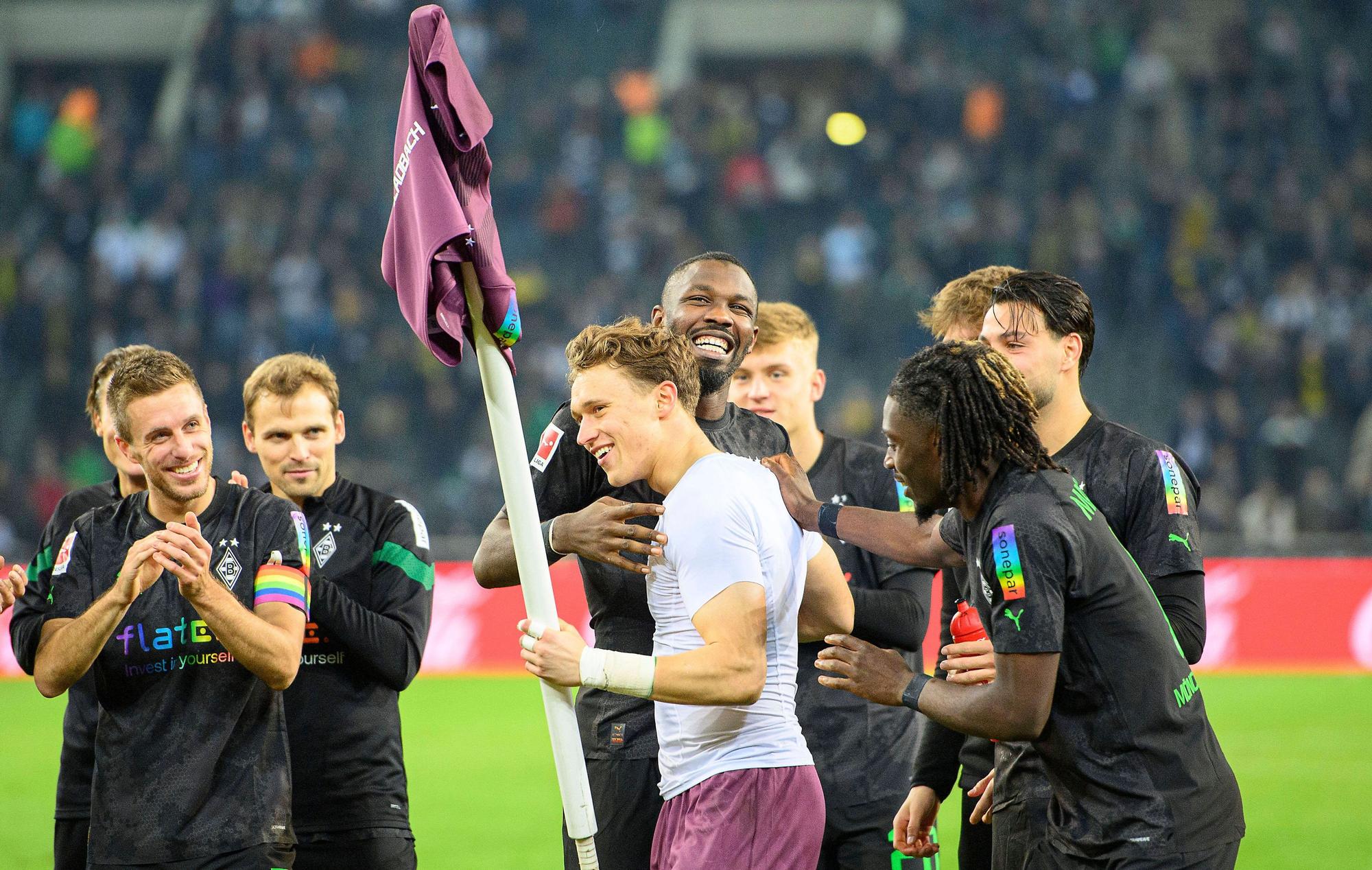 Jubel im Borussia-Park: Die Gladbach-Profis um Stürmer Marcus Thuram feiern nach der 4:2-Gala (11. November 2022) gegen Borussia Dortmund den Heim-Dreier und Torhüter-Talent Jan Olschowsky, der stark gehalten hatte. Olschowsky hält die Eckfahne mit seinem Trikot in der linken Hand.