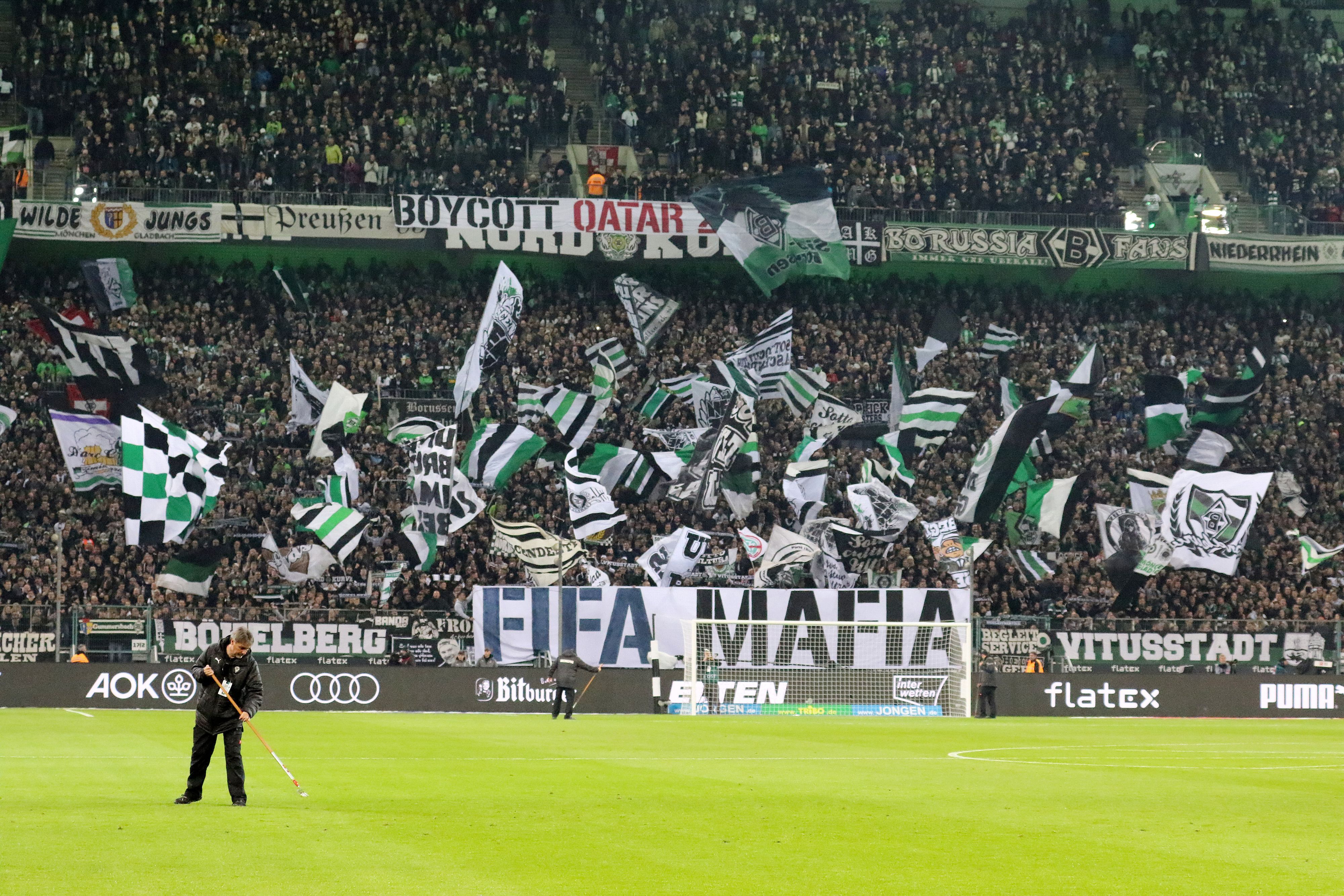 Die Fans in der Nordkurve im Borussia-Park: Dieses Foto zeigt den Anhang von Fußball-Bundesligist Borussia Mönchengladbach vor der Partie gegen Borussia Dortmund (11. November 2022). Im Vordergrund ist noch ein Greenkeeper bei der Arbeit kurz vor Anpfiff zu sehen.
