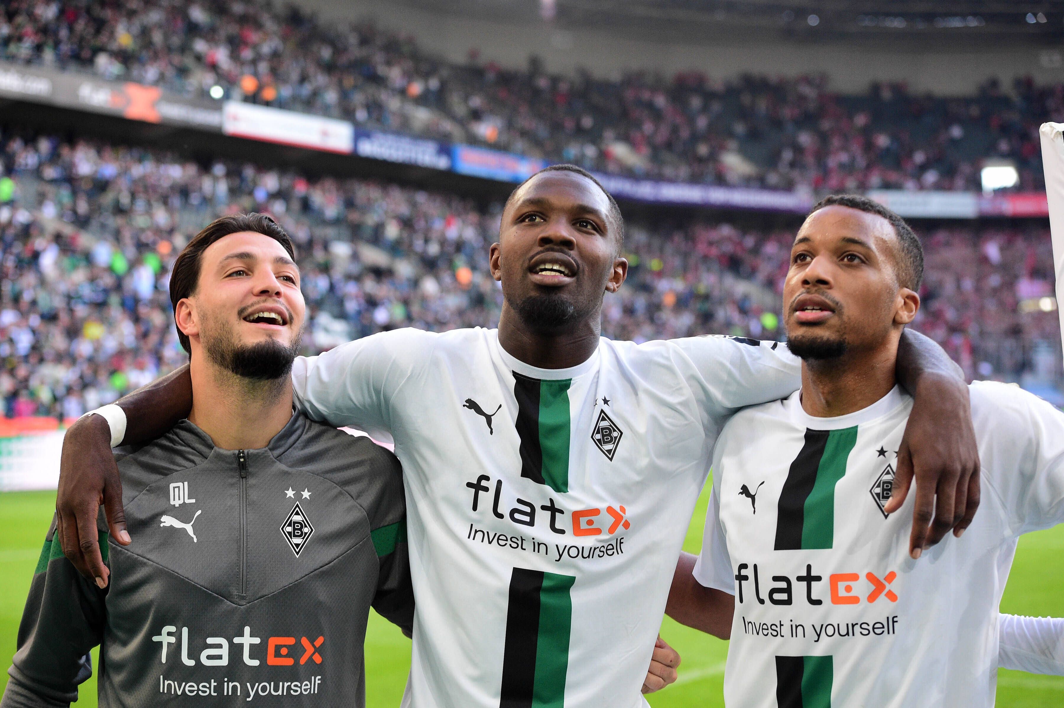Die Gladbach-Profis Alassane Plea, Marcus Thuram und Ramy Bensebaini (v.r.n.l.). Auf diesem Bild sind Borussia-Stars nach dem Derby-Sieg gegen 1. FC Köln am 9. Oktober 2022 im Borussia-Park zu sehen. Die Spieler umarmen sich und lächeln derweil