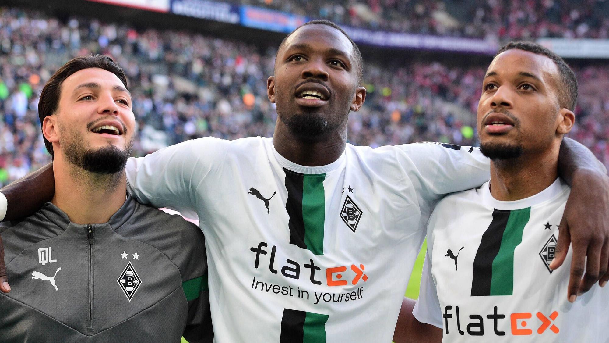Die Gladbach-Profis Alassane Plea, Marcus Thuram und Ramy Bensebaini (v.r.n.l.). Auf diesem Bild sind Borussia-Stars nach dem Derby-Sieg gegen 1. FC Köln am 9. Oktober 2022 im Borussia-Park zu sehen. Die Spieler umarmen sich und lächeln derweil