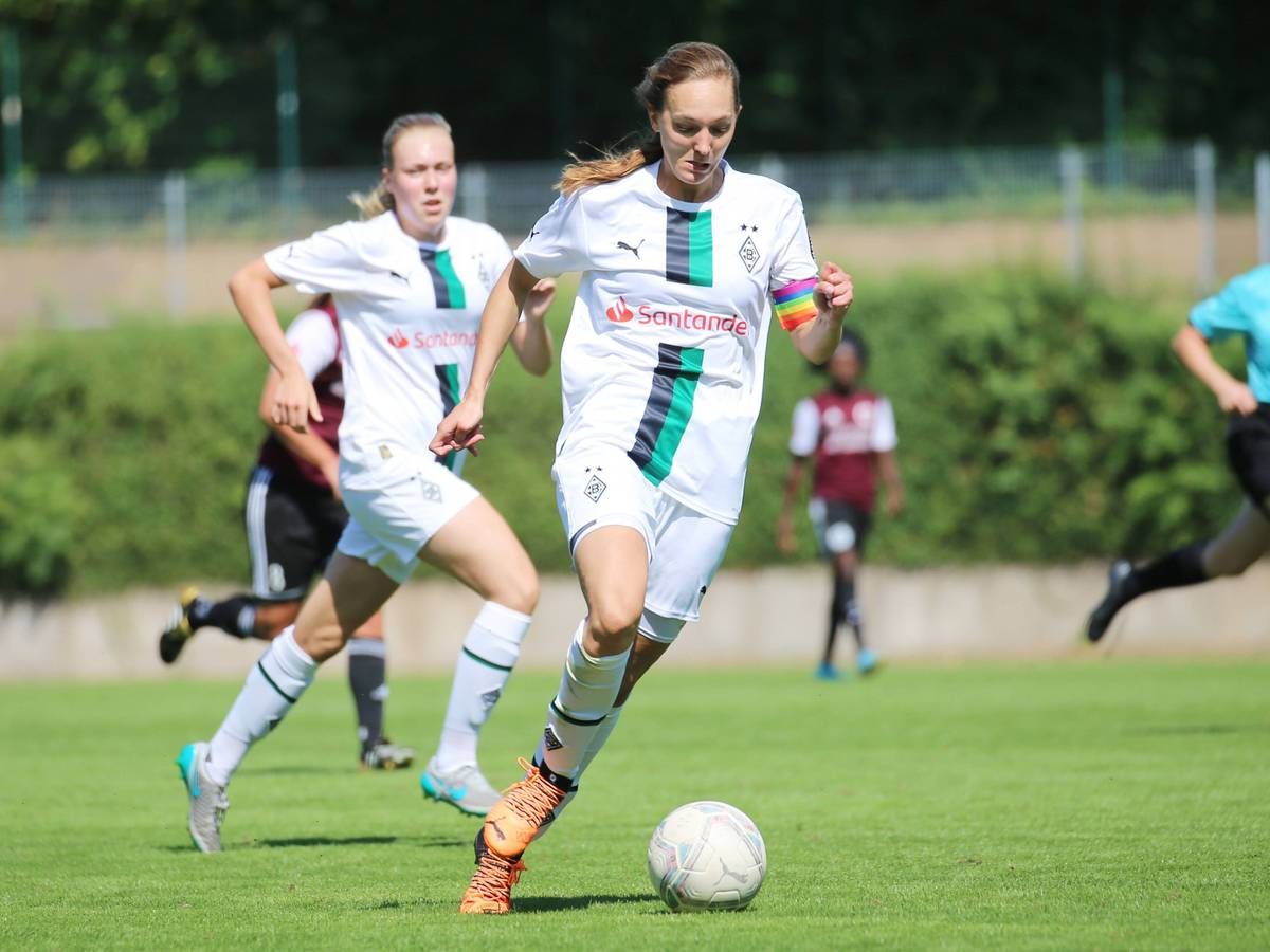 Sarah Schmitz, Spielführerin der Frauenmannschaft von Borussia Mönchengladbach, läuft mit dem Ball am Fuß. Am Arm trägt sie eine regenbogenfarbene Kapitänsbinde.
