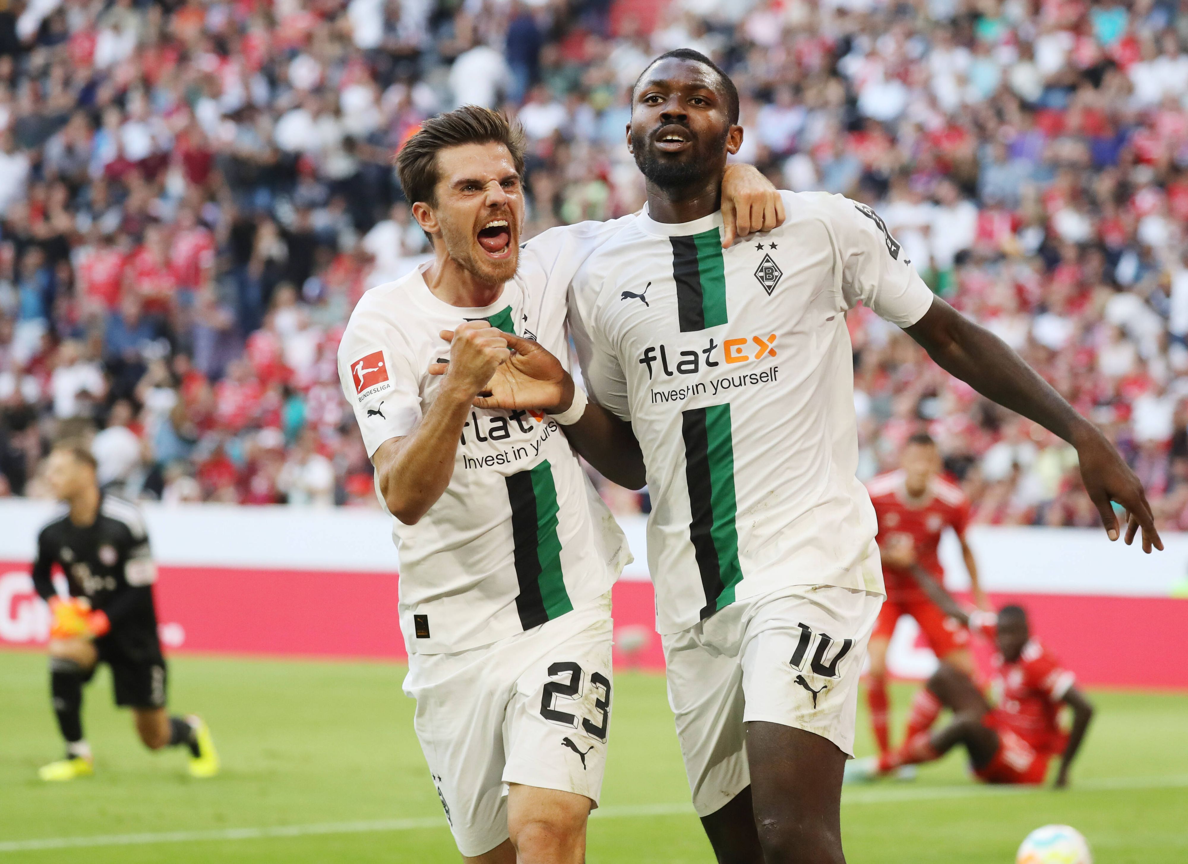 Die Gladbach-Profis Marcus Thuram (r.) und Jonas Hofmann (l,) sind bei der Fußball-WM in Katar für ihr jeweiliges Land im Einsatz. Auf diesem Foto sind die beiden am 27. August 2022 in der Münchner Allianz-Arena zu sehen. Die beiden umarmen sich und jubeln.