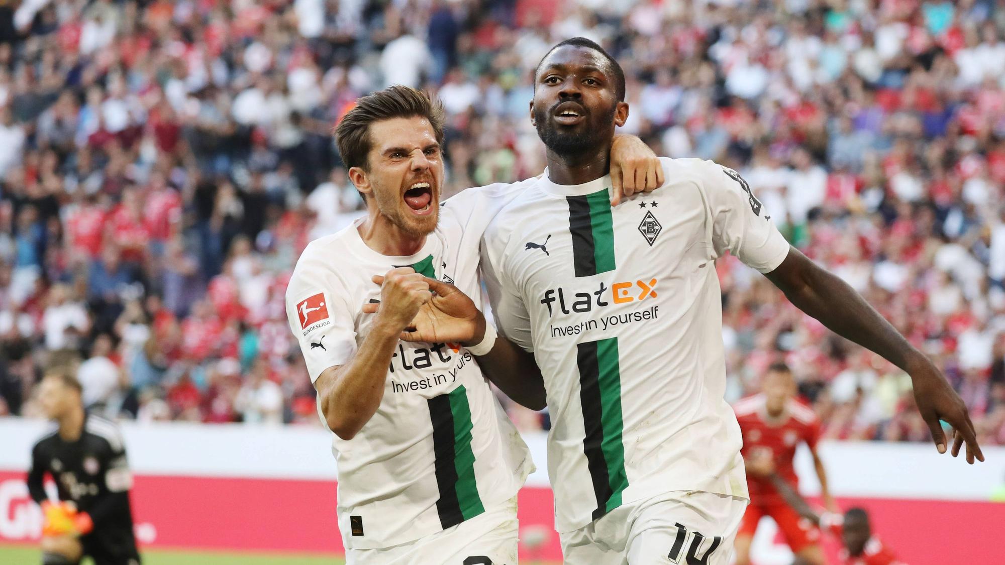 Die Gladbach-Profis Marcus Thuram (r.) und Jonas Hofmann (l,) sind bei der Fußball-WM in Katar für ihr jeweiliges Land im Einsatz. Auf diesem Foto sind die beiden am 27. August 2022 in der Münchner Allianz-Arena zu sehen. Die beiden umarmen sich und jubeln.