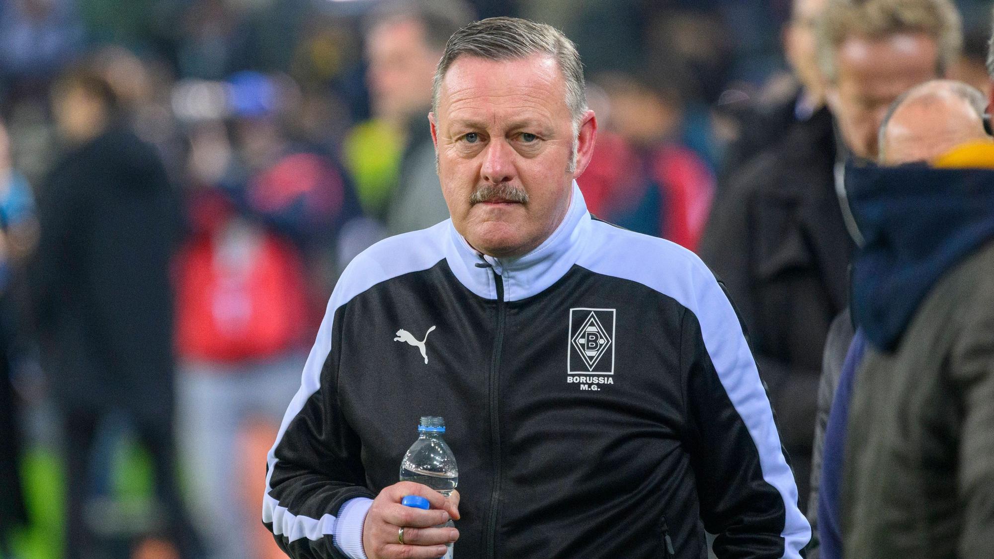 Gladbach-Manager Roland Virkus, auf diesem Foto am 11. November 2022 im Borussia-Park zu sehen. Virkus trägt eine dunkle Trainingsjacke und hält eine Flasche Mineralwasser in seiner rechten Hand.