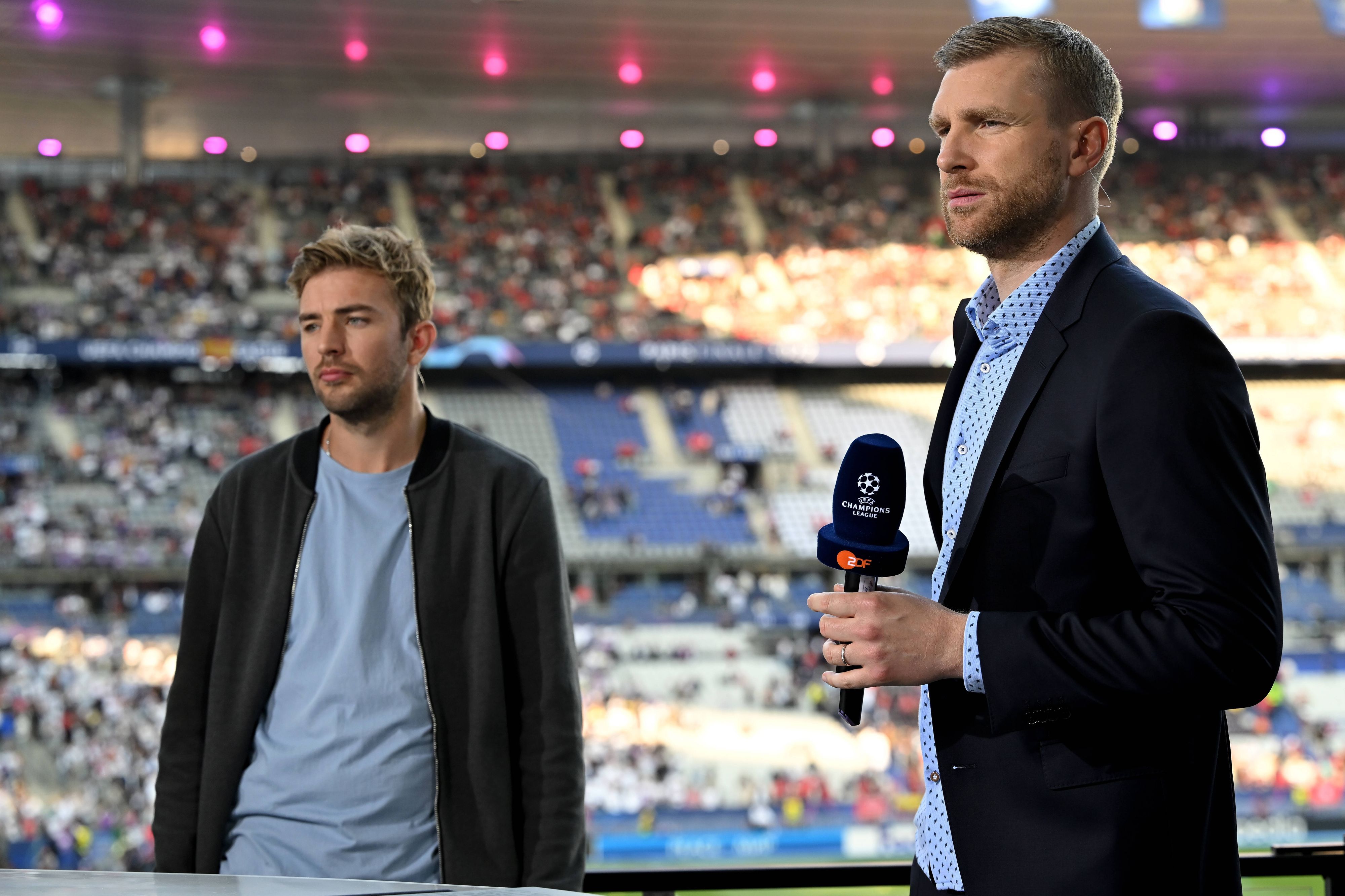 Gladbach-Profi Christoph Kramer (l.) und Per Mertesacker am 28. Mai 2022 beim Champions-League-Finale in Paris. Mertesacker hält ein Mikrofon in der rechten Hand.