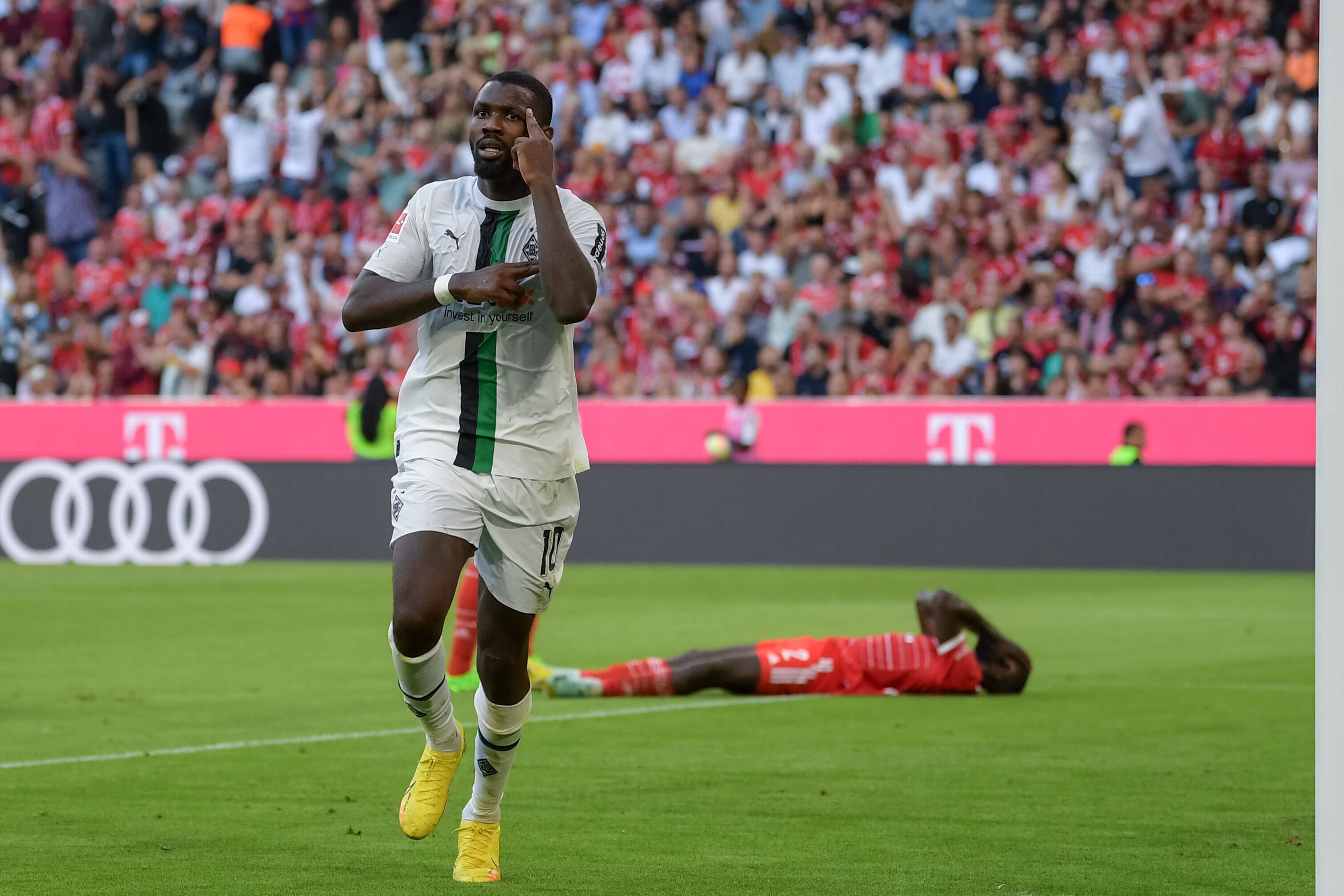 Marcus Thuram erzielt ein Tor für Borussia Mönchengladbach gegen den FC Bayern München am 27. August 2022 und jubelt, während Bayern-Verteidiger Dayot Upamecano auf dem Boden liegt.