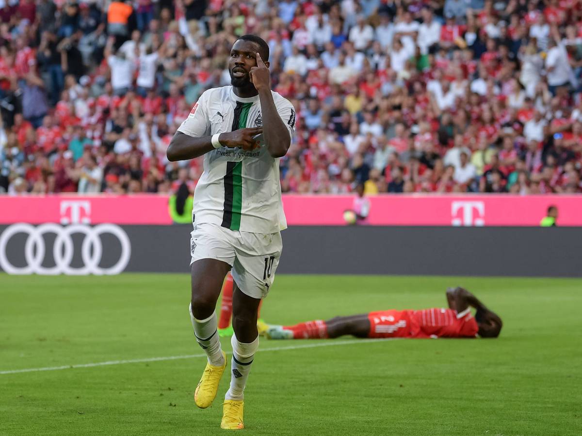 Marcus Thuram erzielt ein Tor für Borussia Mönchengladbach gegen den FC Bayern München am 27. August 2022 und jubelt, während Bayern-Verteidiger Dayot Upamecano auf dem Boden liegt.
