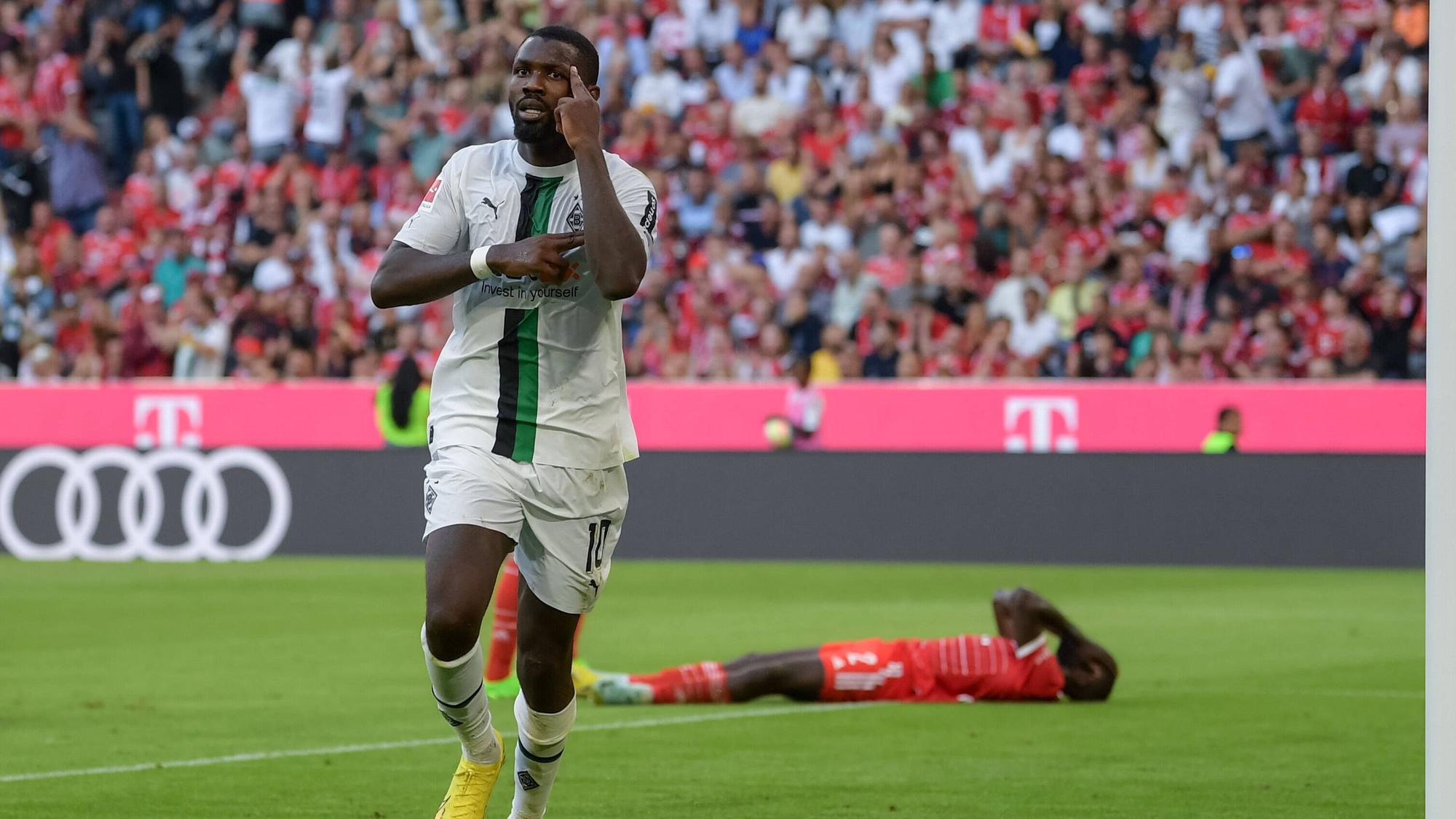 Marcus Thuram erzielt ein Tor für Borussia Mönchengladbach gegen den FC Bayern München am 27. August 2022 und jubelt, während Bayern-Verteidiger Dayot Upamecano auf dem Boden liegt.