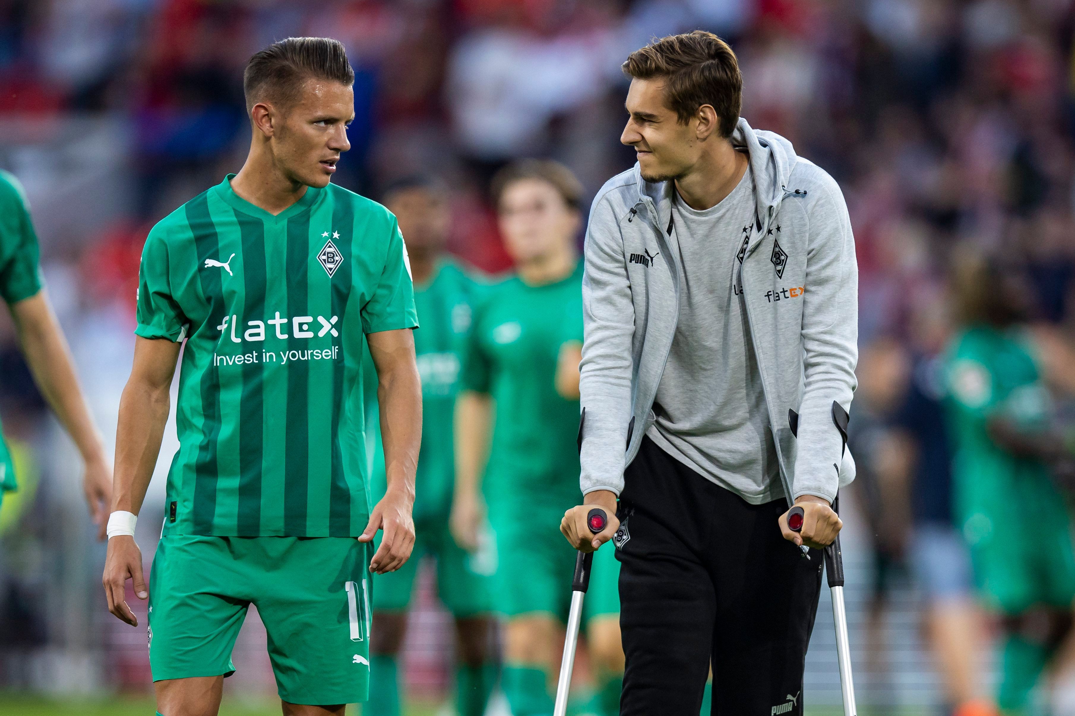 Hannes Wolf spricht mit seinem Teamkollegen Florian Neuhaus von Borussia Mönchengladbach, der wegen einer Verletzung auf Krücken ist.