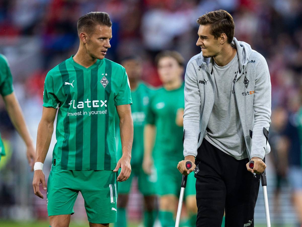 Hannes Wolf spricht mit seinem Teamkollegen Florian Neuhaus von Borussia Mönchengladbach, der wegen einer Verletzung auf Krücken ist.