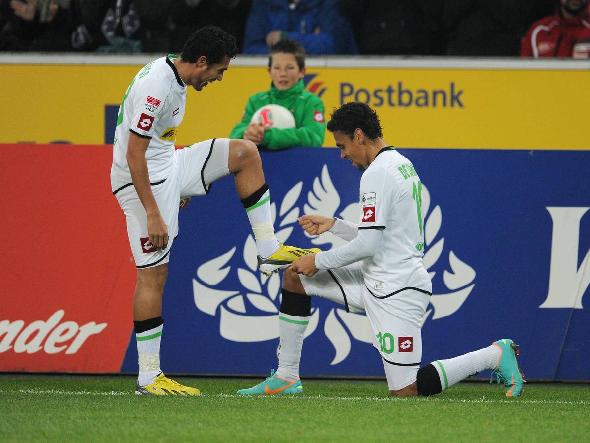 Zeige mir deinen Zauberhuf! Juan Arango (l.) und Igor de Camargo mit einer Jubelgeste am 28. November 2012 im Borussia-Park. Am Samstag (17. Dezember 2022) kehren die beiden zum Legendenspiel nach Gladbach zurück. Auf diesem Foto hat Arango seinen linken Fuß auf den Oberschenkel von de Camargo gestellt. Dieser kniet vor Arango.