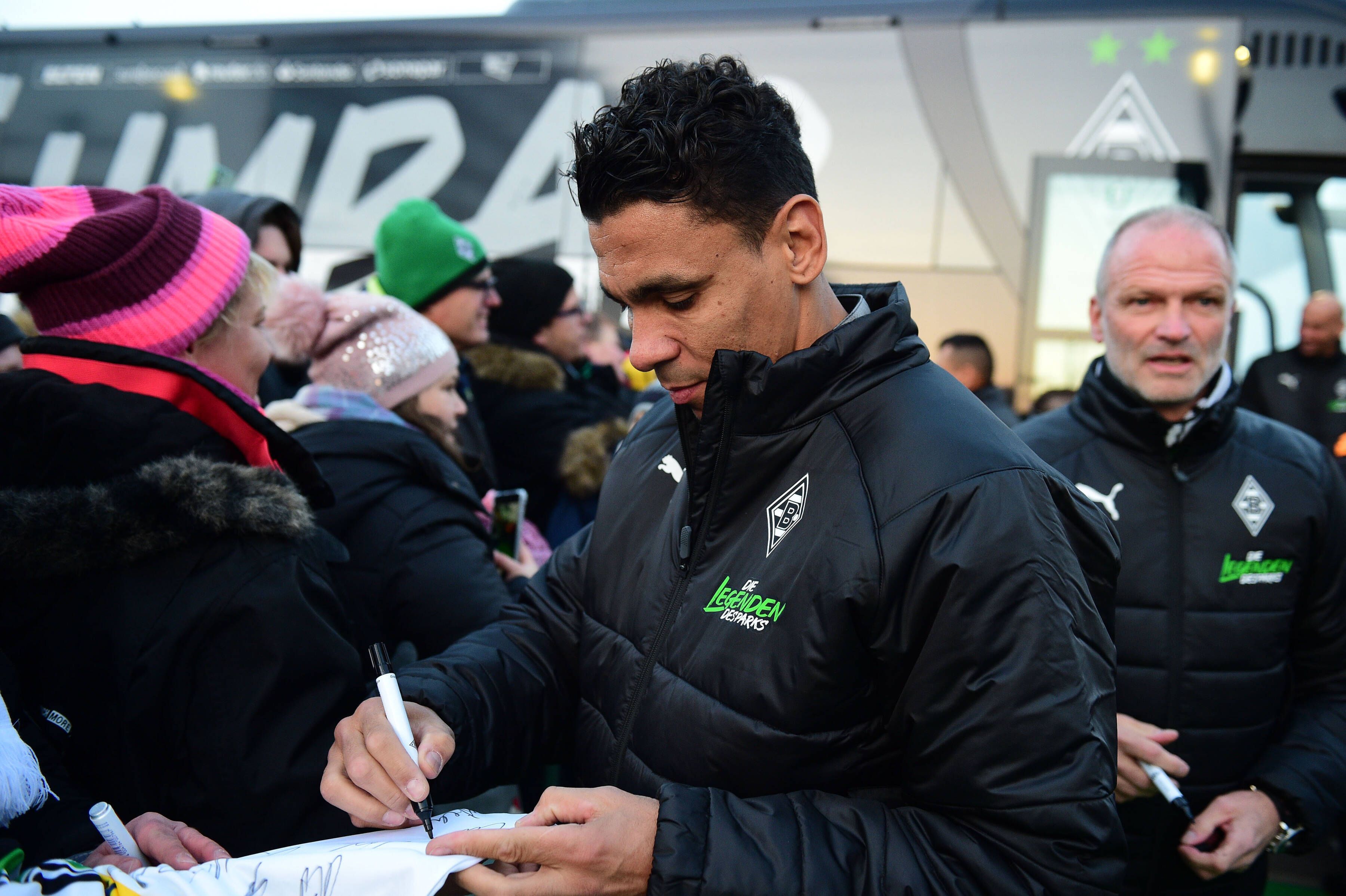 Gladbachs Relegations-Held Igor de Camargo wird von Tausenden Fohlen-Fans am Samstag (17. Dezember 2022) im Borussia-Park empfangen. Im Hintergrund ist Ex-Trainer Holger Fach zu sehen. De Camargo schreibt Autogramme.