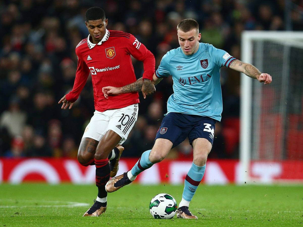 Jordan Beyer bestreitet im blauen Auswärtstrikot des FC Burnley einen Zweikampf mit Marcus Rashford, Spieler von Manchester United.