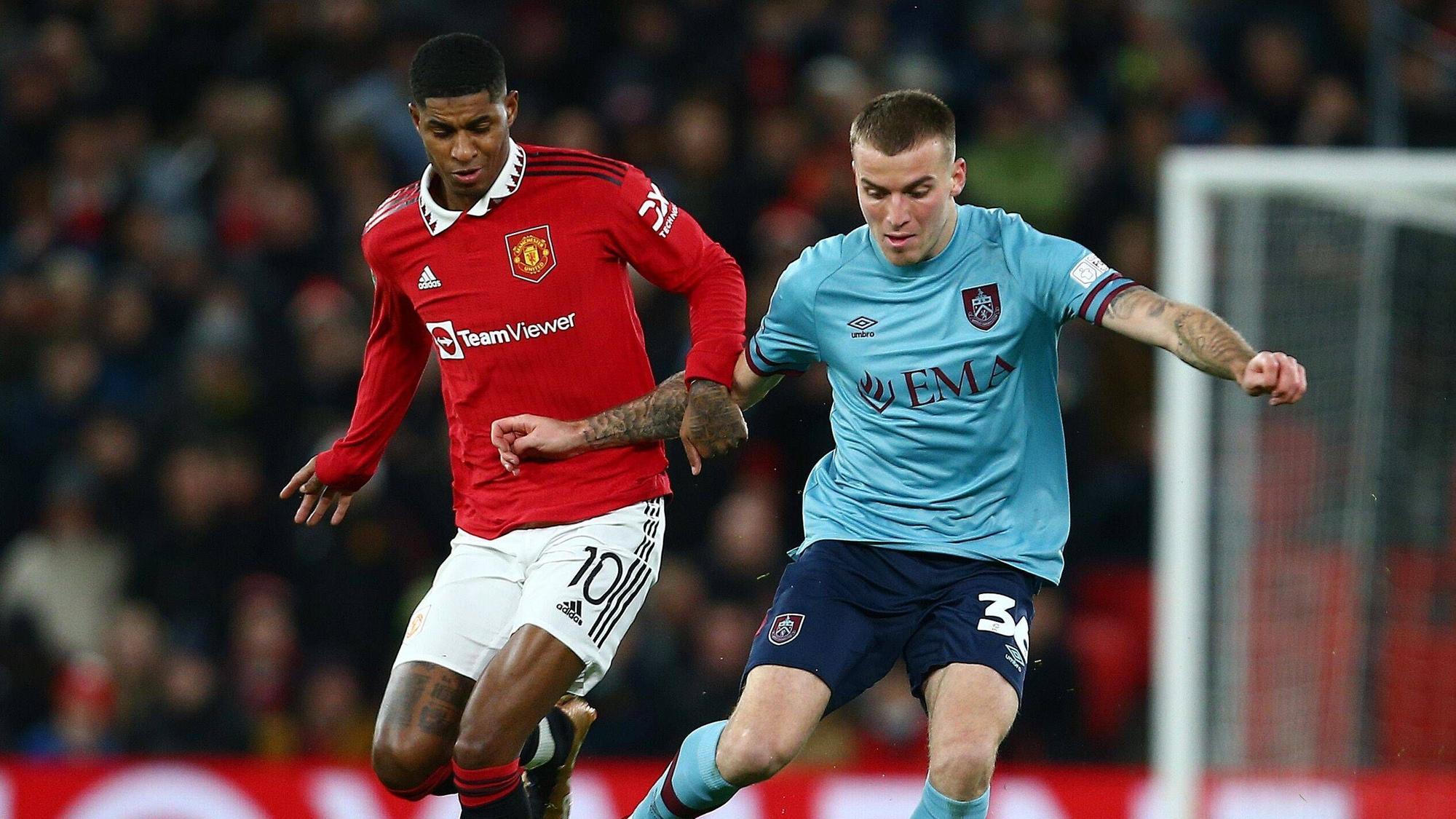 Jordan Beyer bestreitet im blauen Auswärtstrikot des FC Burnley einen Zweikampf mit Marcus Rashford, Spieler von Manchester United.