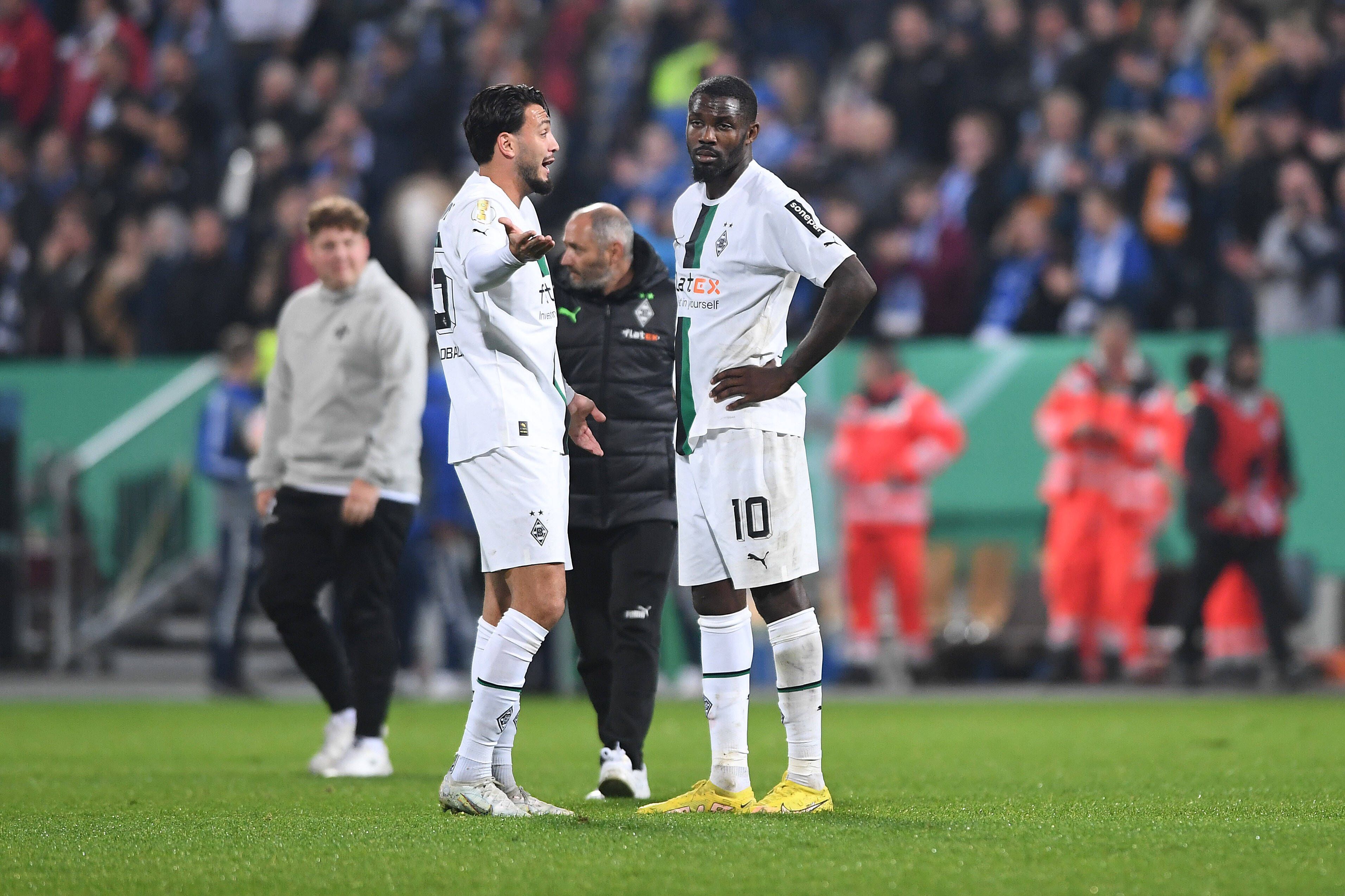 Ramy Bensebaini und Marcus Thuram stehen nach dem Spiel im DFB-Pokal bei Darmstadt 98 auf dem Rasen zusammen und reden. Bensebaini gestikuliert nach der Niederlage mit den Armen, Thuram wirkt enttäuscht.