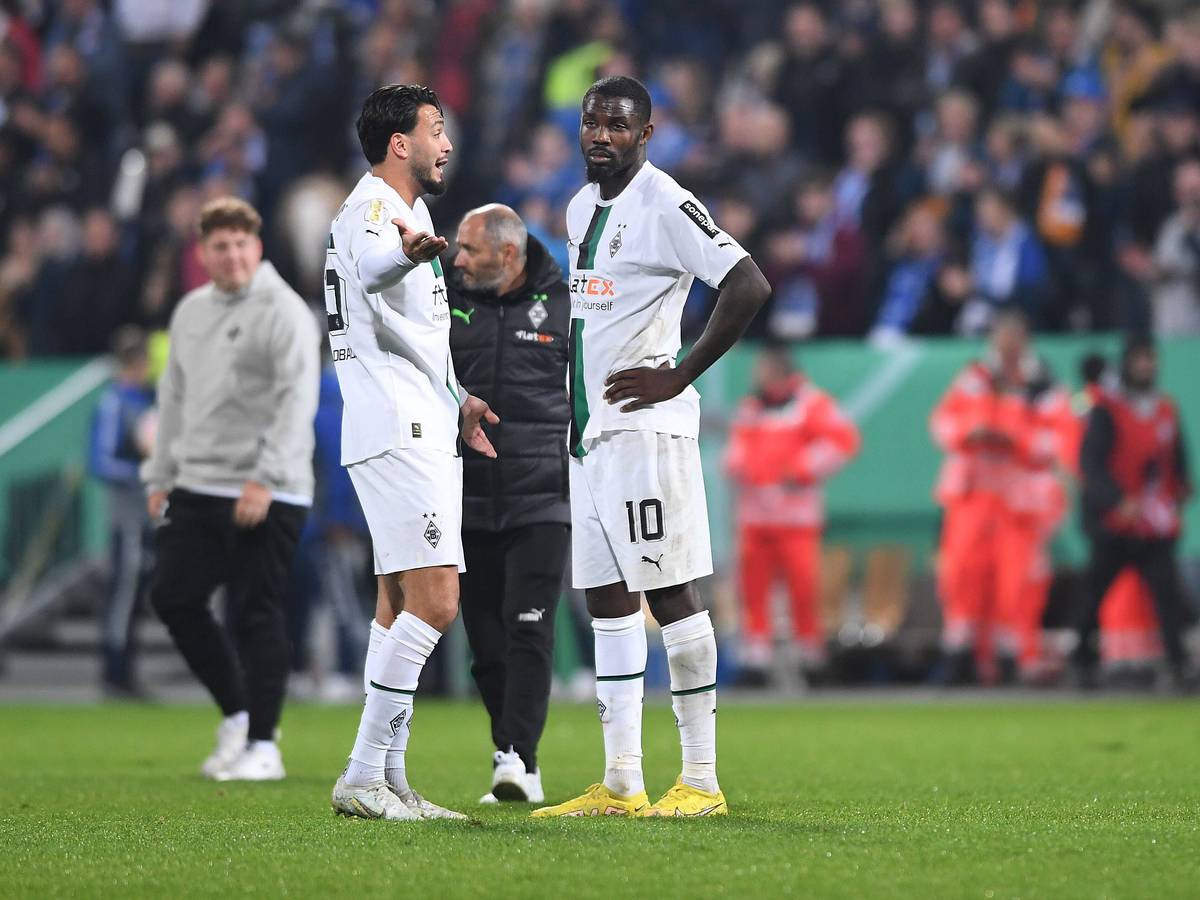 Ramy Bensebaini und Marcus Thuram stehen nach dem Spiel im DFB-Pokal bei Darmstadt 98 auf dem Rasen zusammen und reden. Bensebaini gestikuliert nach der Niederlage mit den Armen, Thuram wirkt enttäuscht.
